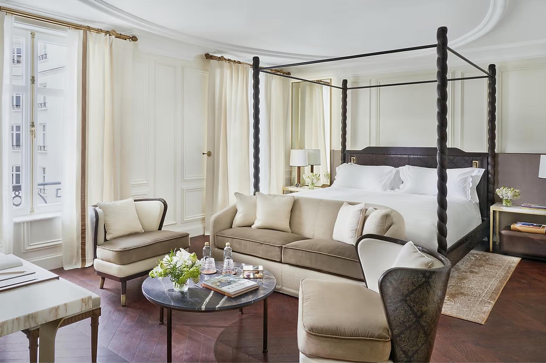 Bedroom with black four-poster bed, cream furnishings, and bay window seating