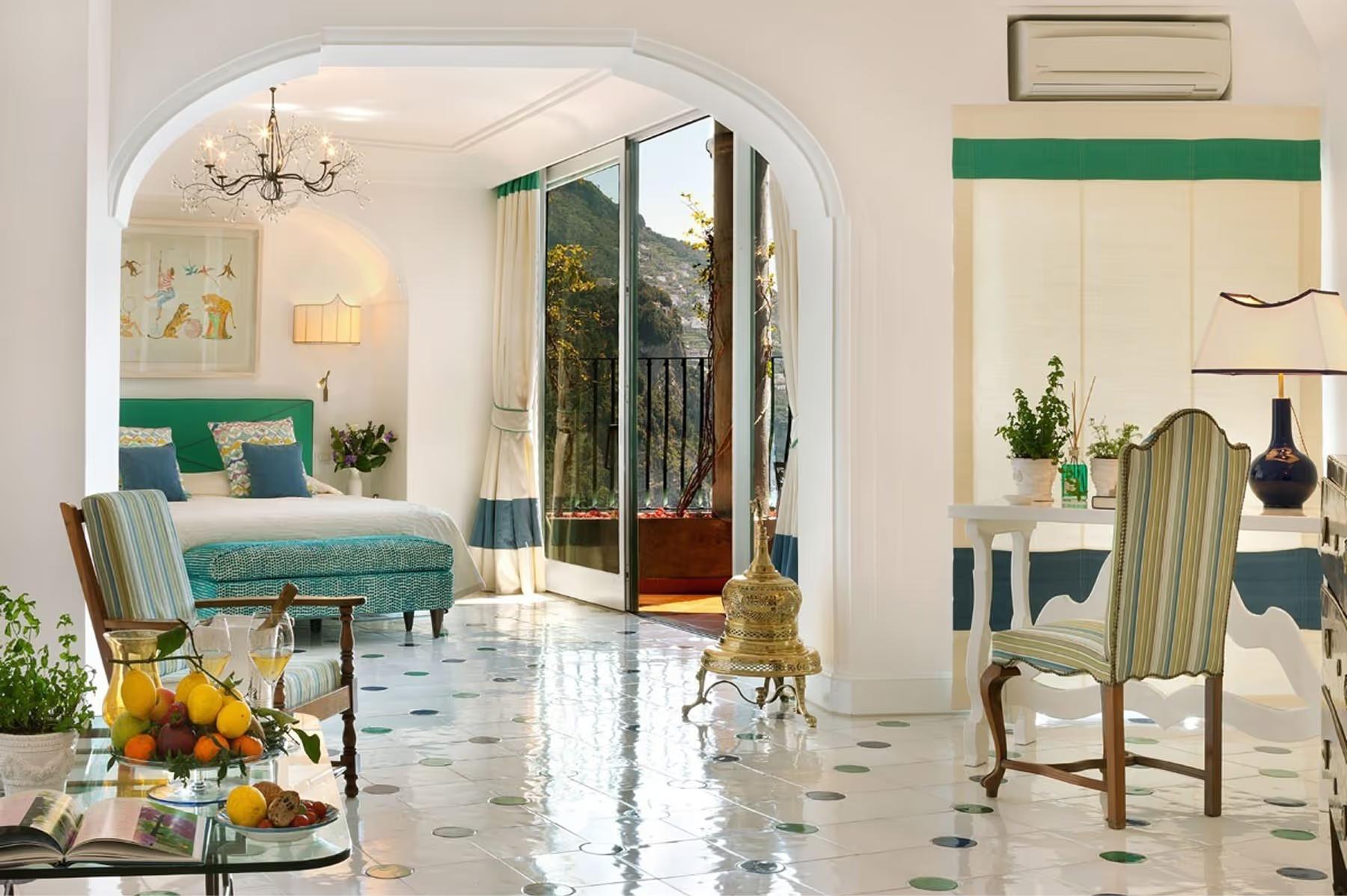 Bright interior lounge with turquoise seating, arched entryway, marble flooring, and tall window