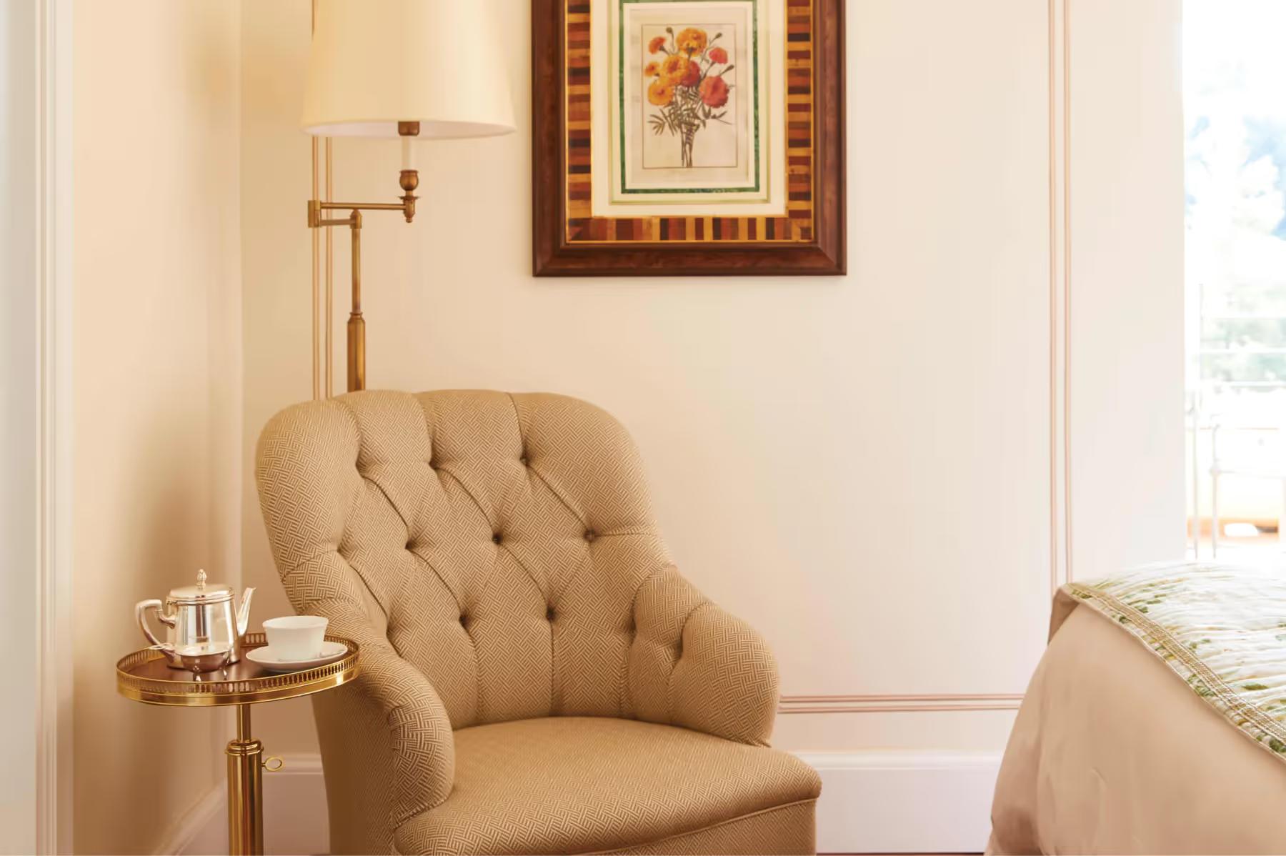 A sitting area with green velvet sofa, floral cushions, and botanical wallpaper