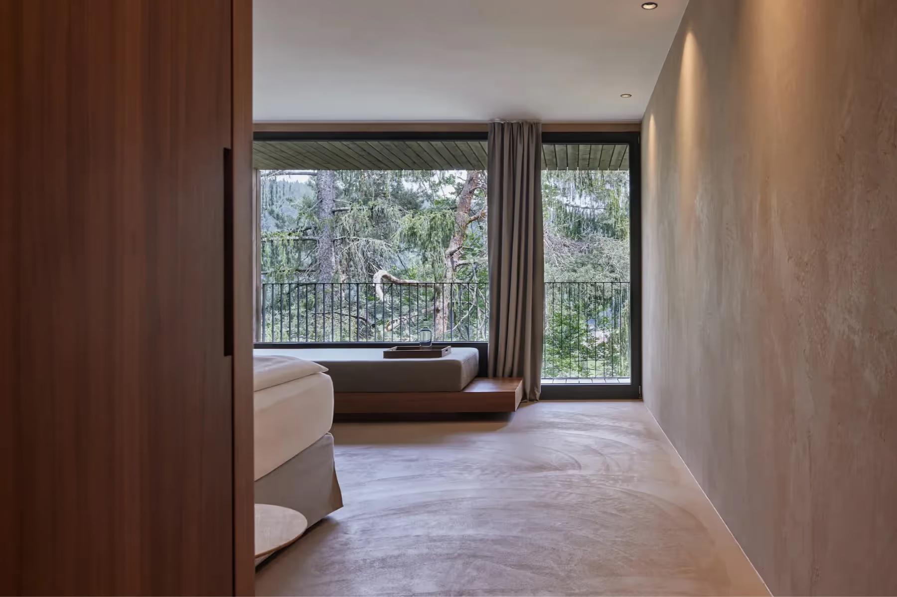 Spacious room with wood-framed glass doors opening to forest views and terraced landscape