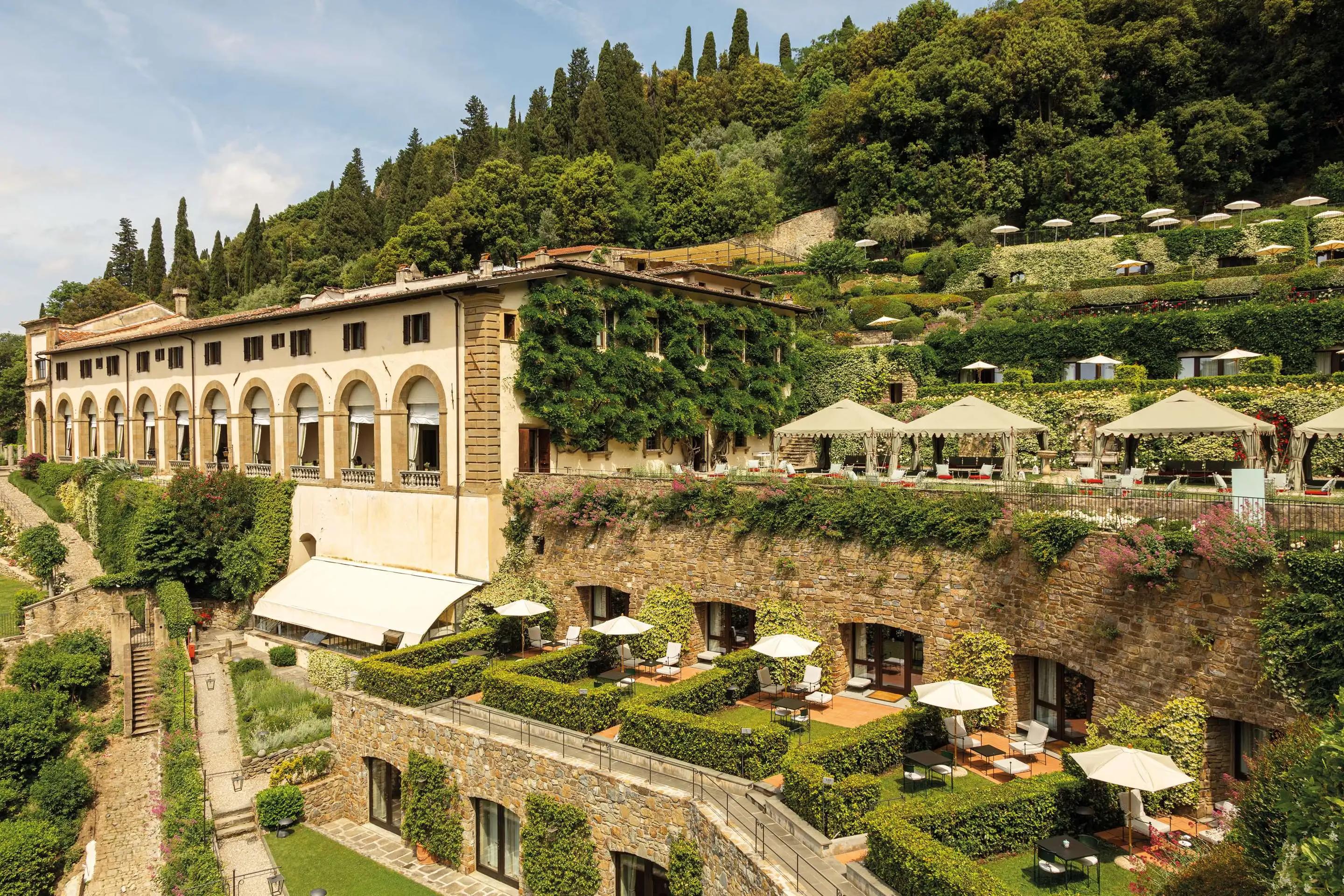 The arched loggia wing of Villa San Michele above terraced gardens set with umbrellas and cabanas