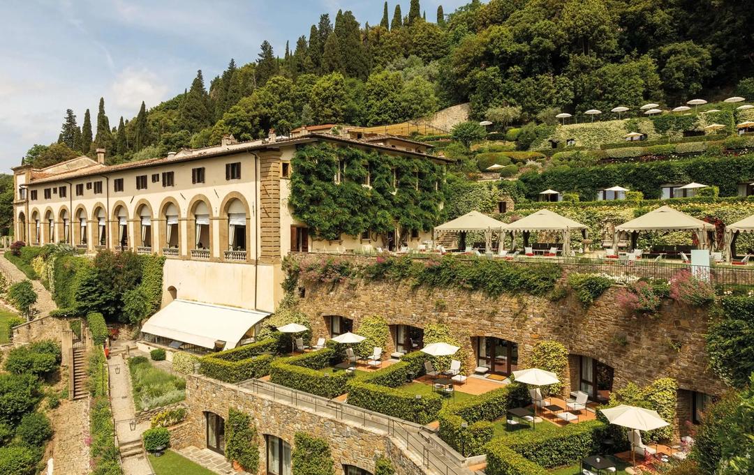 The arched loggia wing of Villa San Michele above terraced gardens set with umbrellas and cabanas