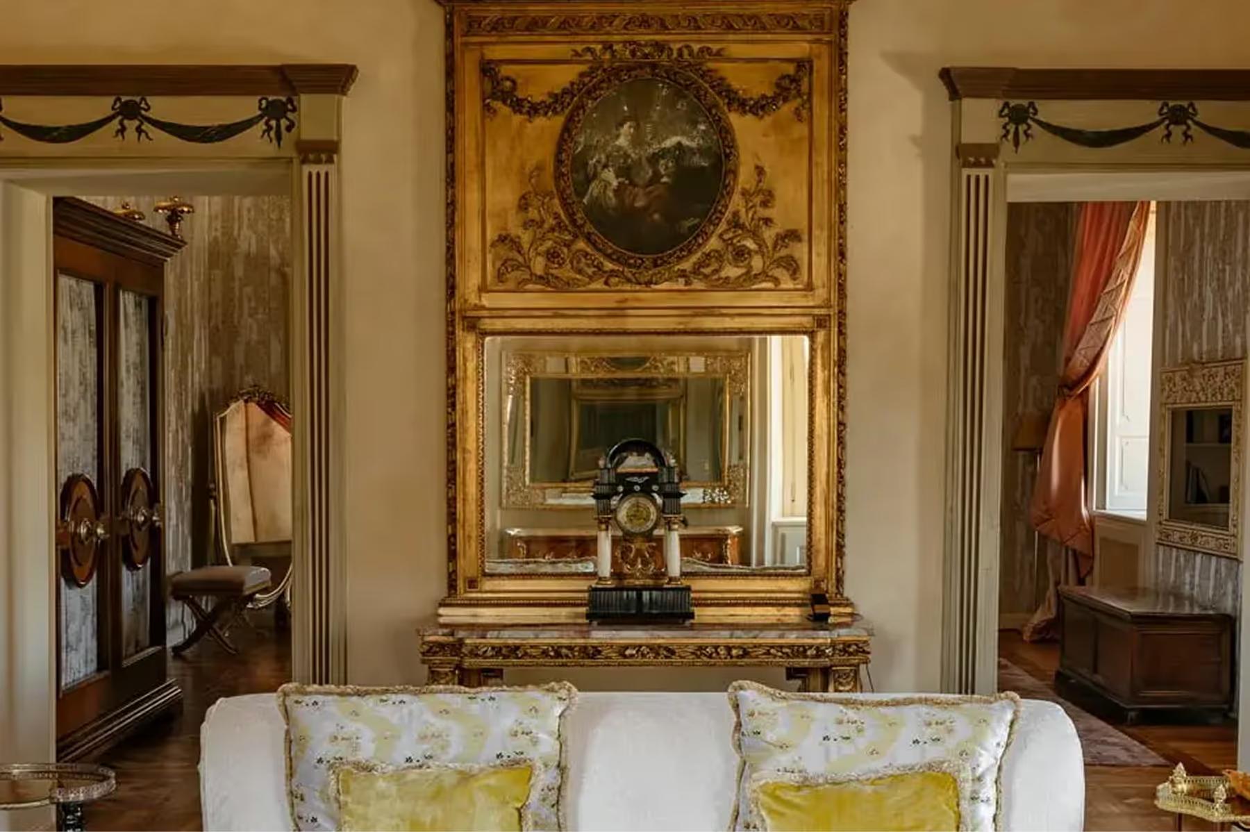A seating area with ornate gold mirrors, gilded console, and yellow damask cushions