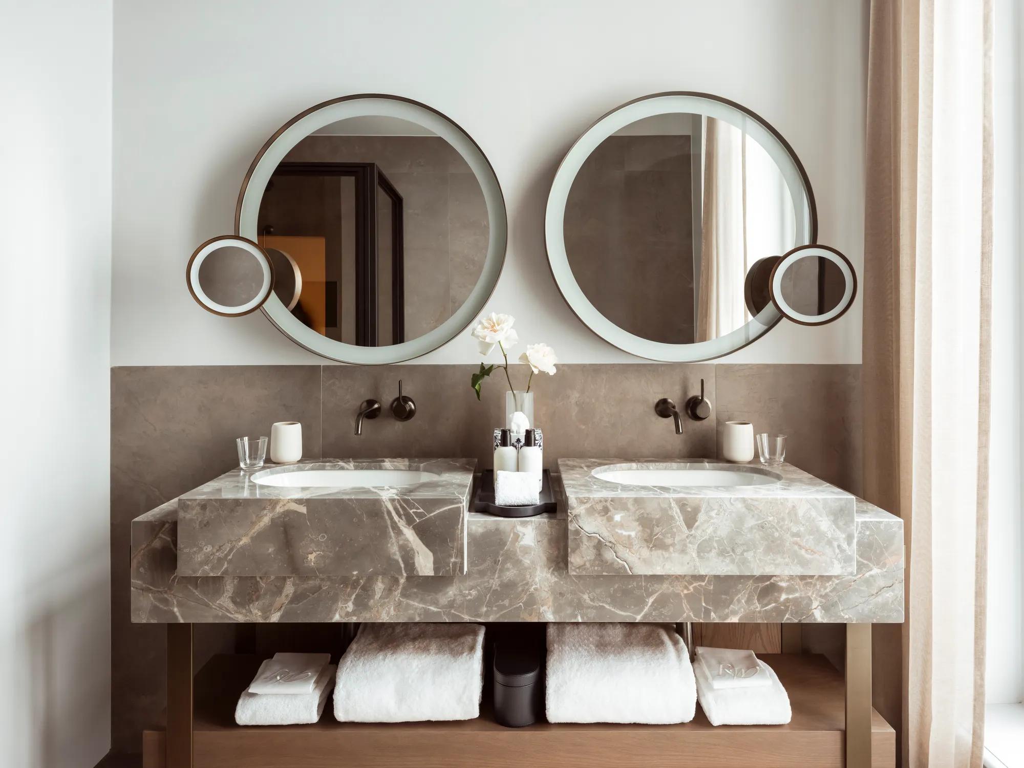 Rosewood Amsterdam: a Grand Premier Room bathroom with a marble double vanity and two round mirrors