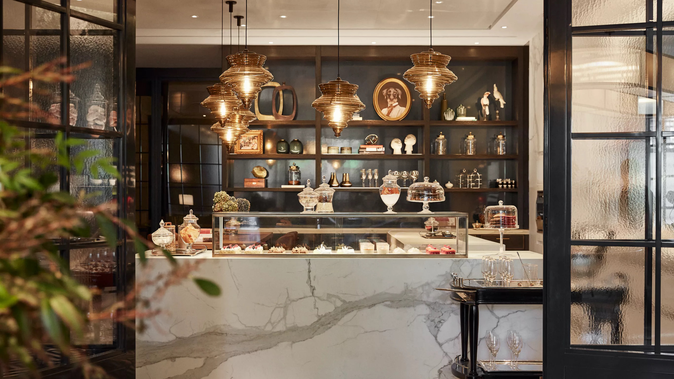 A bar counter with gold pendant lighting, glass display cabinets, and back-lit shelving