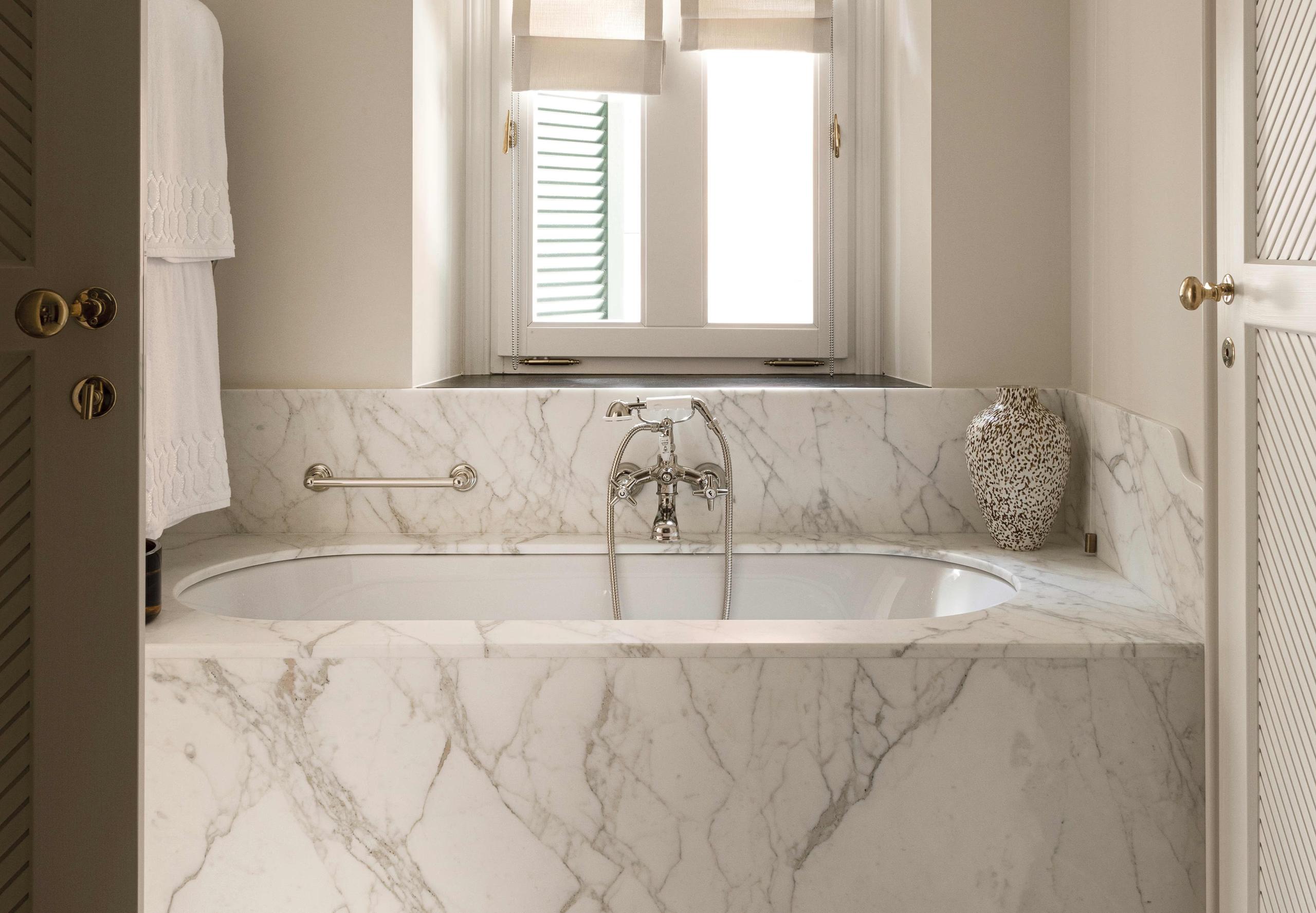 Marble bathroom with arched window and white fixtures