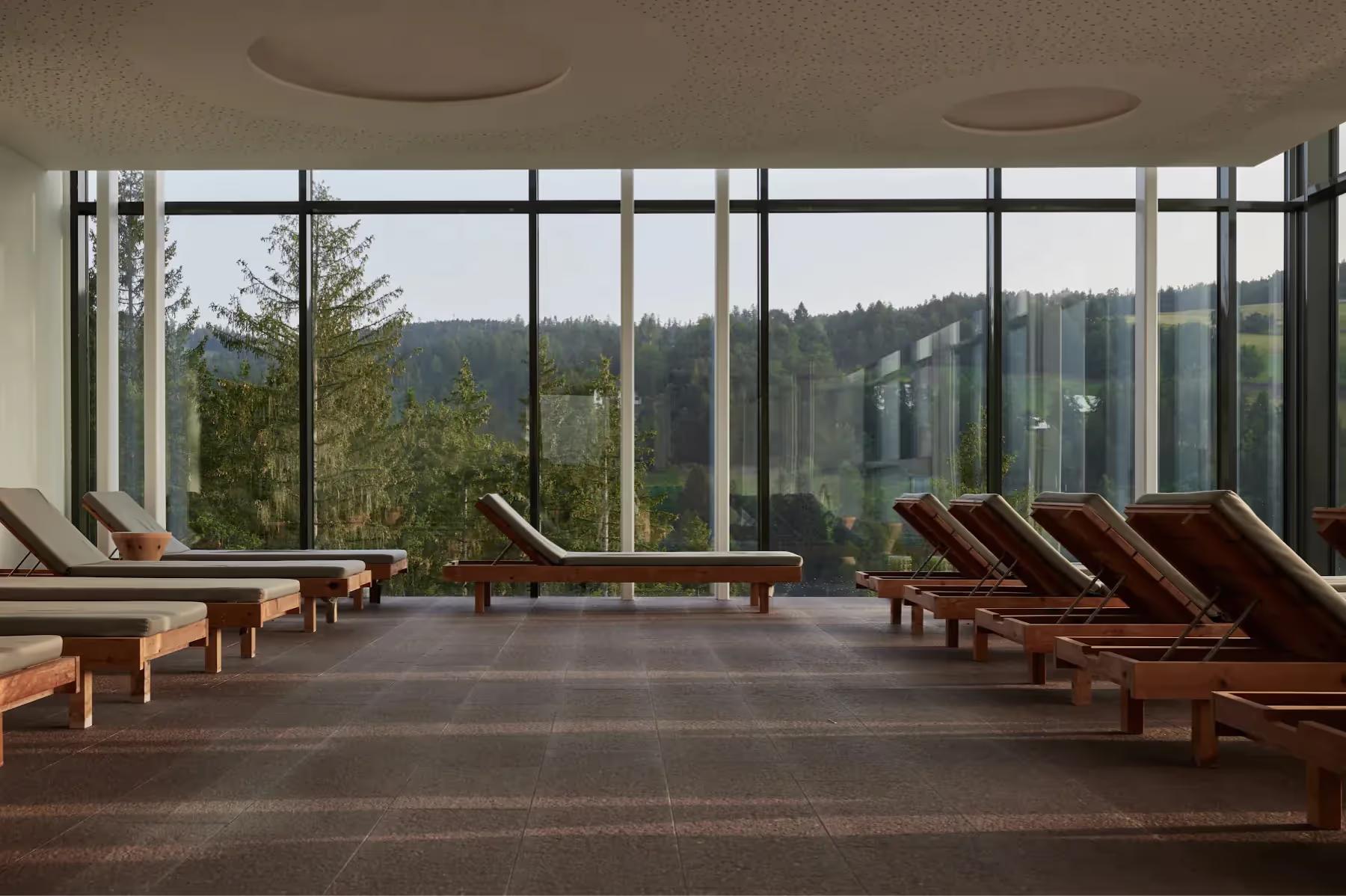 Hotel Saltus: spa relaxation room with wooden loungers and panoramic windows framing mountain views