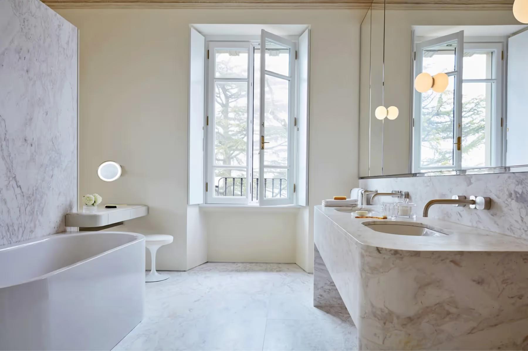 Villa Patrizia: a marble bathroom with tub, freestanding sink, and French doors opening to terrace
