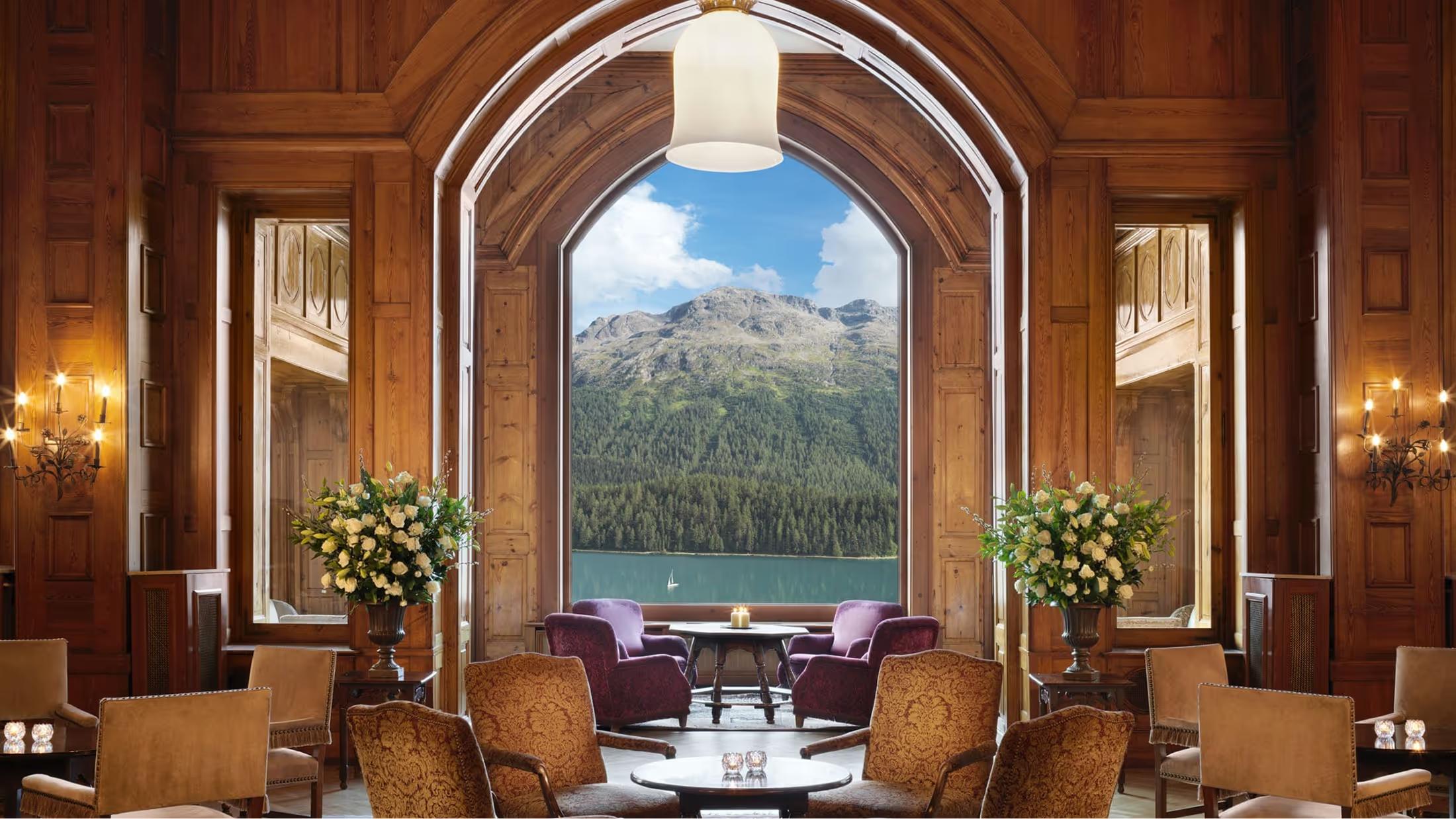 Wood-paneled lounge with arched doorway framing snowy mountain peak