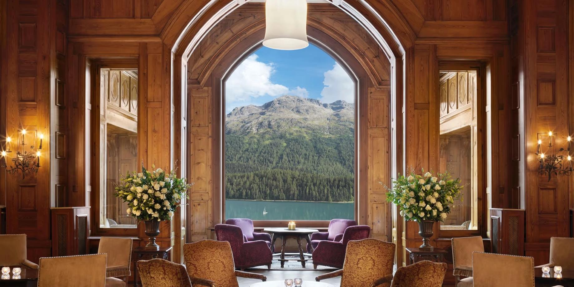 Wood-paneled lounge with arched doorway framing snowy mountain peak