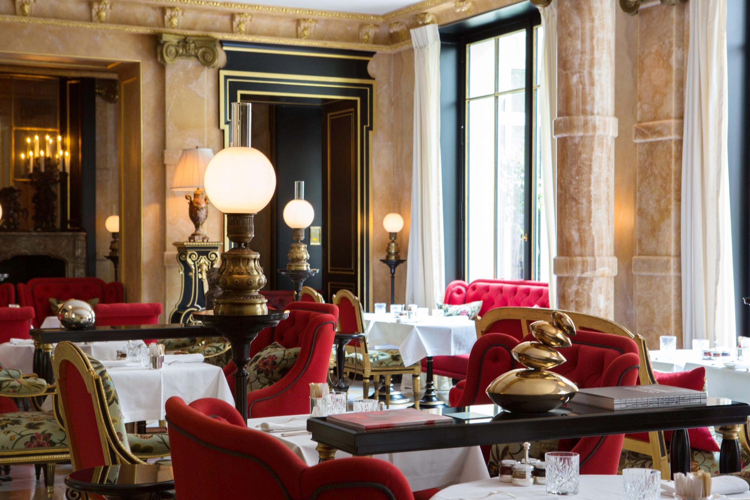 La Réserve Paris: a dining room with cream walls, soft pendant lighting, and red velvet banquettes