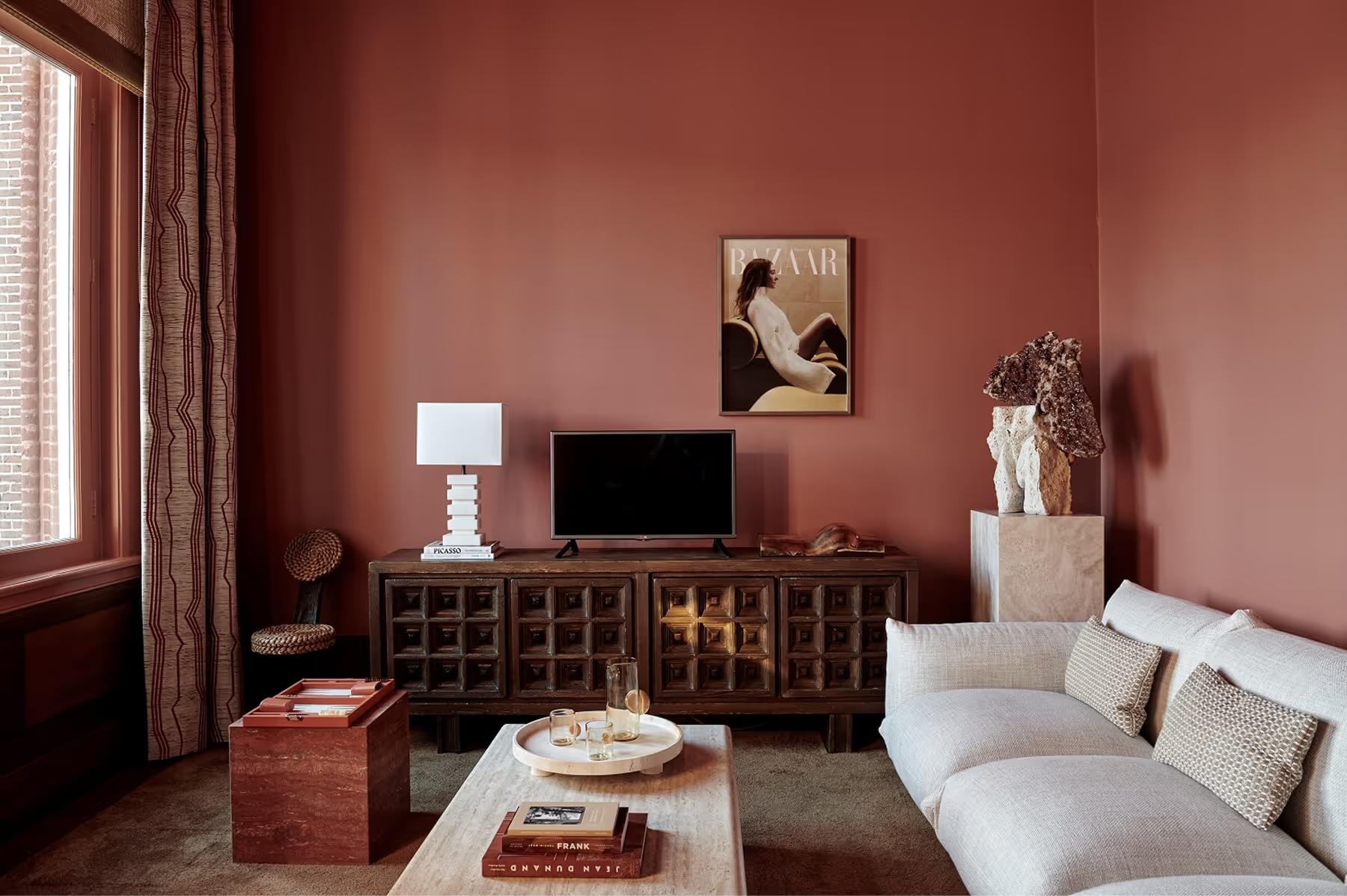 De L’Europe Amsterdam: suite sitting area with terracotta accent wall, cream upholstered seating, and entertainment console