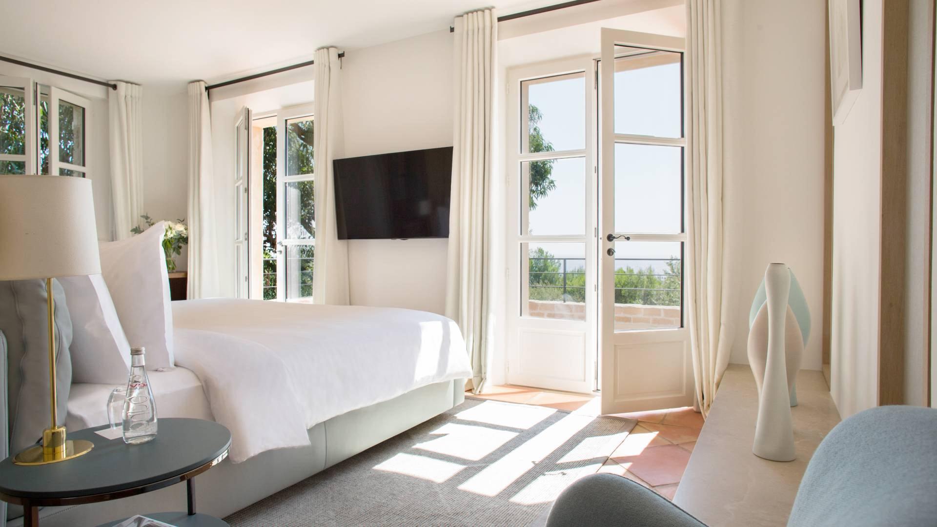 La Réserve Ramatuelle: bright bedroom with white bed and open doors to terraced seating