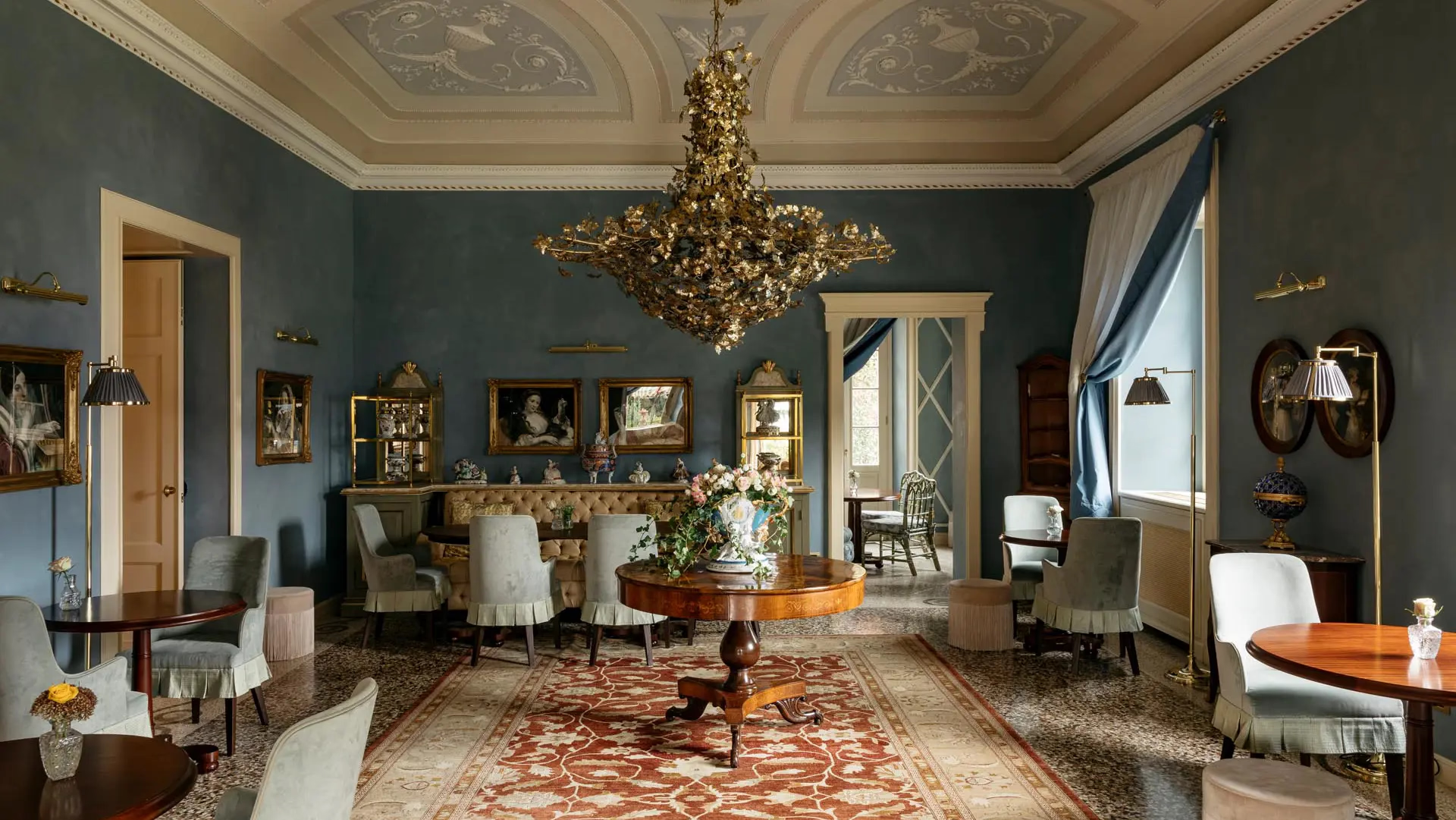 Passalacqua: a drawing room with teal walls, gold furnishings, chandelier, and patterned rug