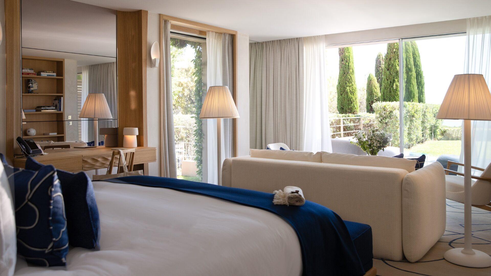 La Réserve Ramatuelle: bedroom with blue-upholstered bed and doors opening to garden