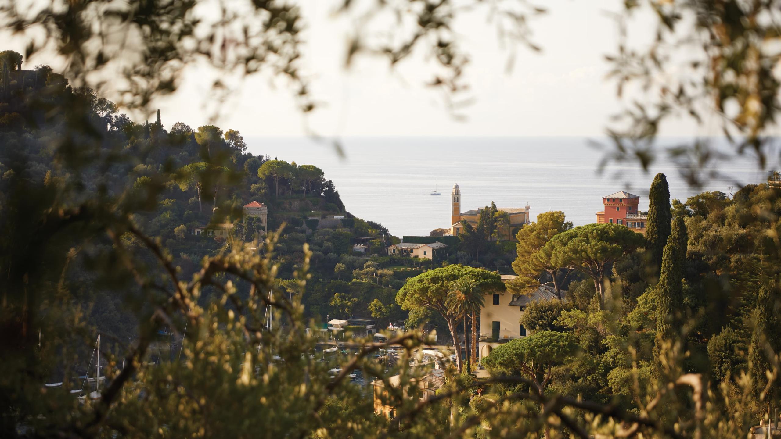 Splendido: the hotel hillside surrounded by trees framing a distant sea view under pale sky