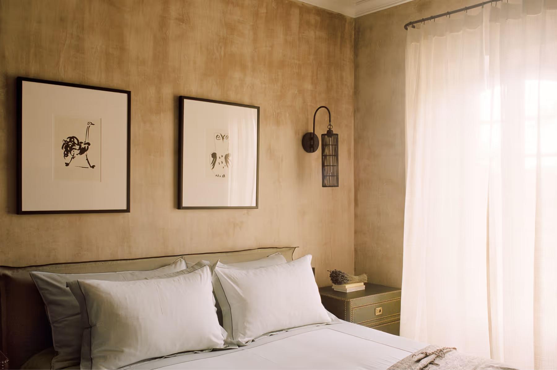 Le Mas de Chabran: bedroom with taupe upholstered headboard, framed prints on wall, and soft lighting