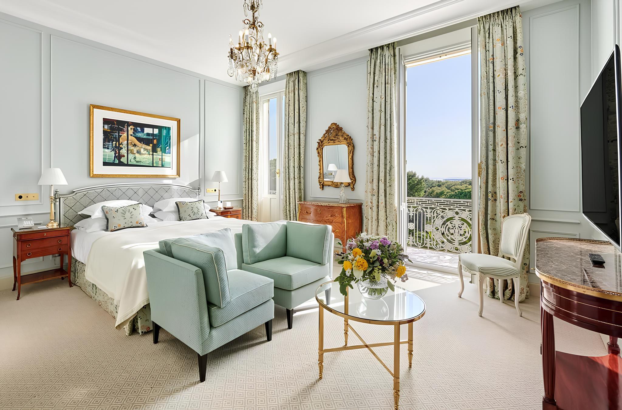 Hôtel du Cap-Eden-Roc: a suite with white marble furniture, light walls, patterned curtains, and views over the grounds