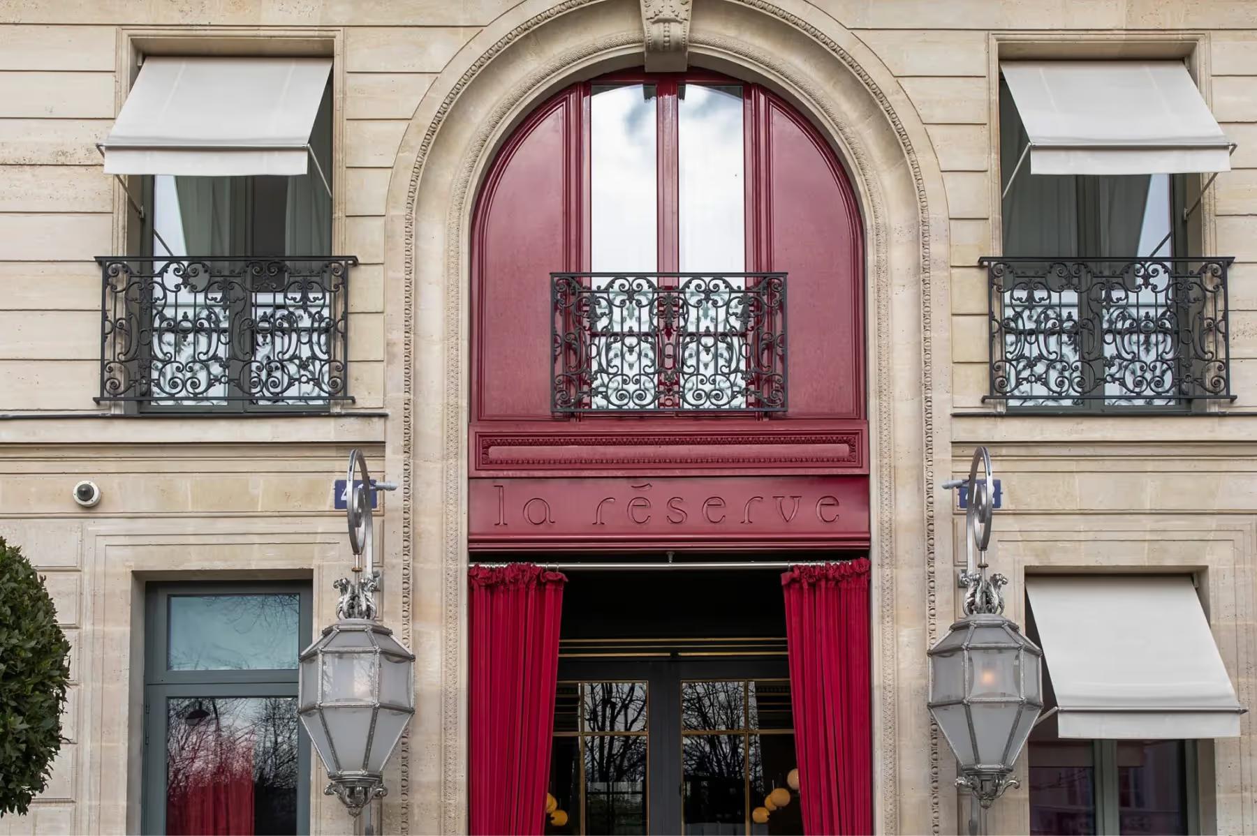 La Réserve Paris: the salmon-red arched entrance with brass lanterns on either side