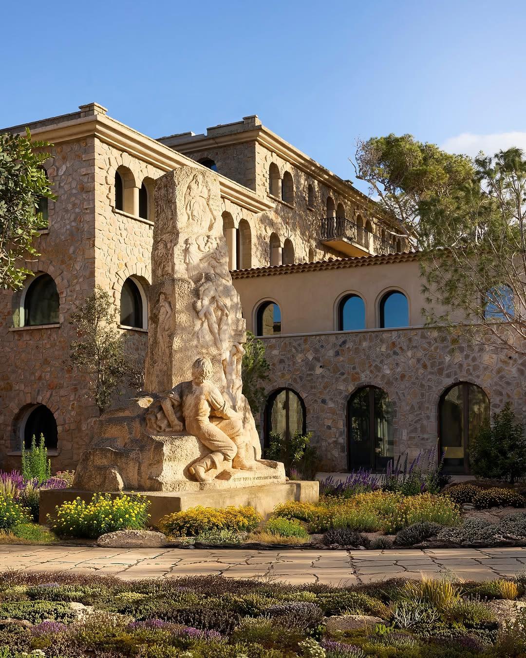 A carved stone monument to Paul Ricard stands amid Mediterranean garden plantings