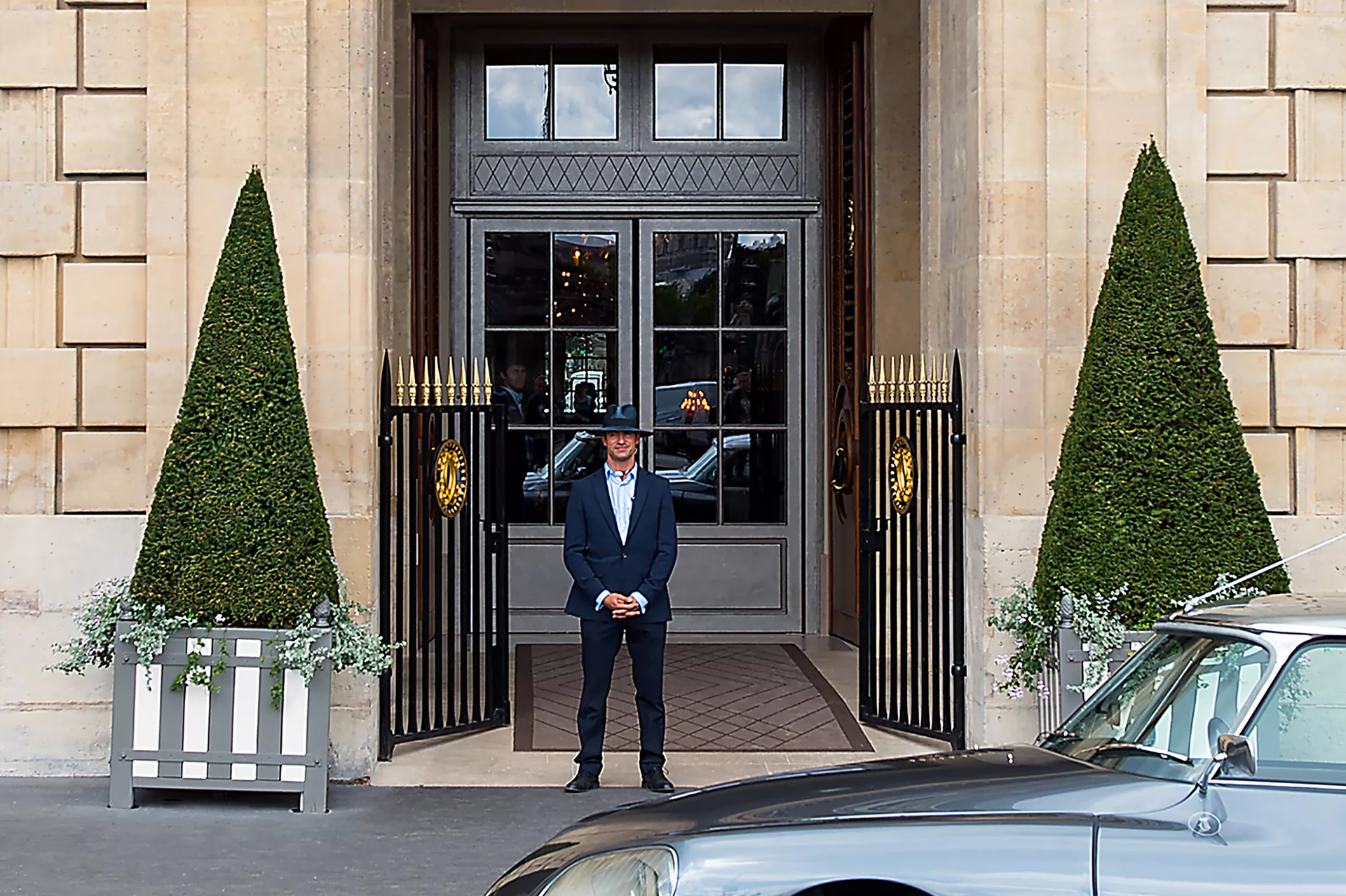 Hotel entrance with doorman, striped awning, and traditional Parisian facade