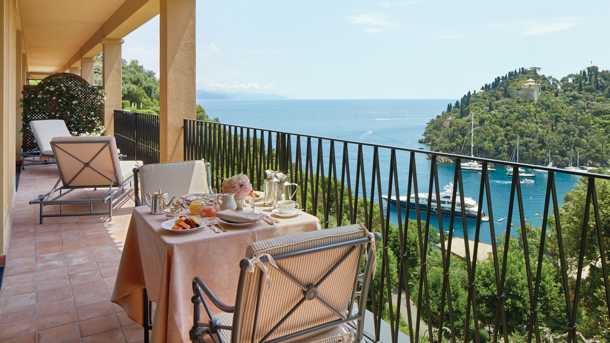 Splendido: a dining table set on a terrace with sea view, framed by pergola and metal railings