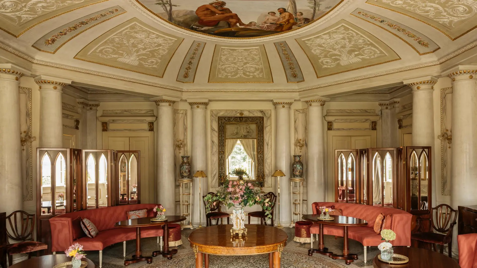 Passalacqua: a cream-colored neoclassical salon with ornate ceiling, red velvet seating, and tall mirrors