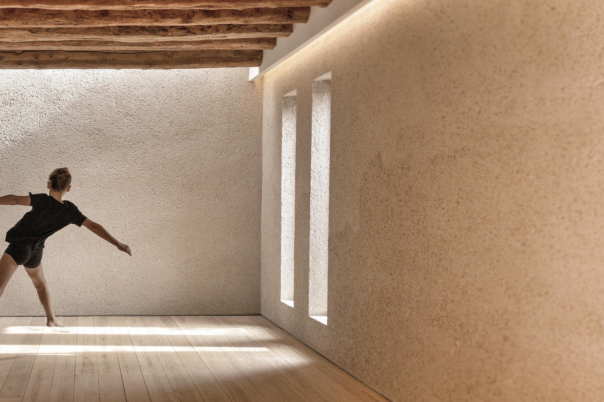Es Racó d’Artà: movement or dance studio with soaring wooden ceiling, bright sidelighting, and person in mid-motion