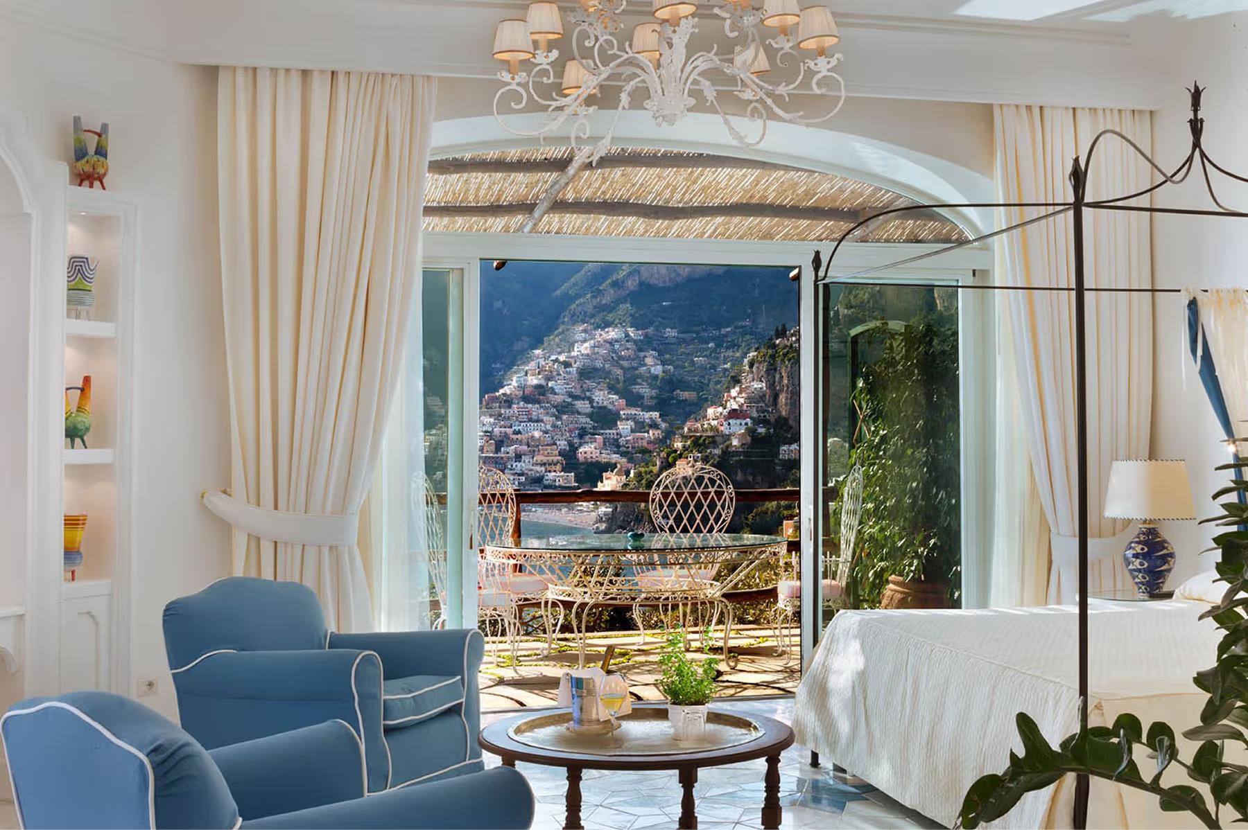 Il San Pietro di Positano: bedroom with draped canopy, full windows, curved architectural details, and expansive coastal outlook