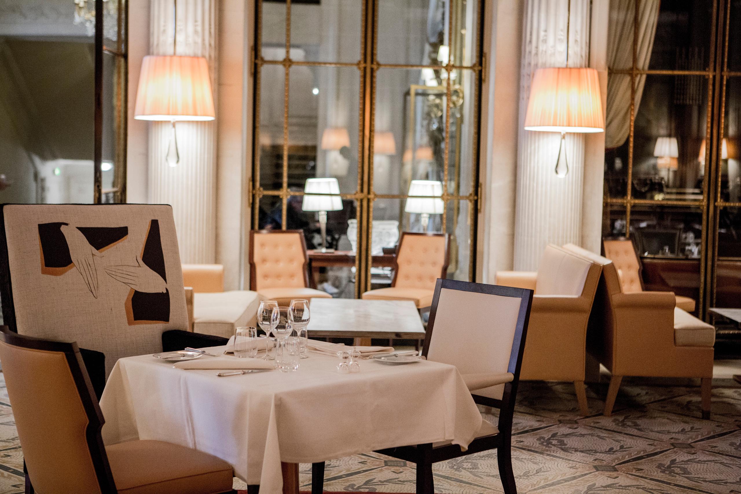 Le Meurice: an intimate dining room with white tablecloths, classical furnishings, and soft warm lighting