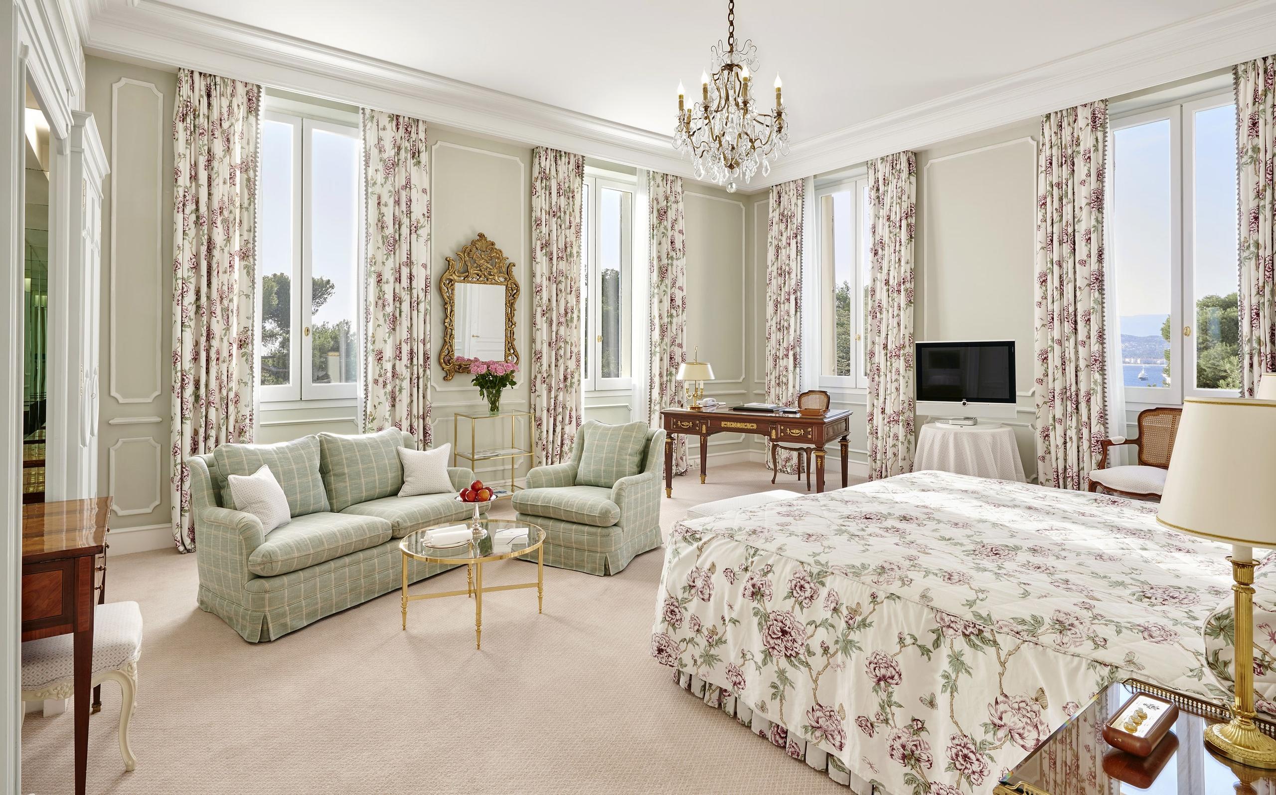 Hôtel du Cap-Eden-Roc: a spacious suite with tall windows, dual sitting areas, patterned drapery, and classical décor