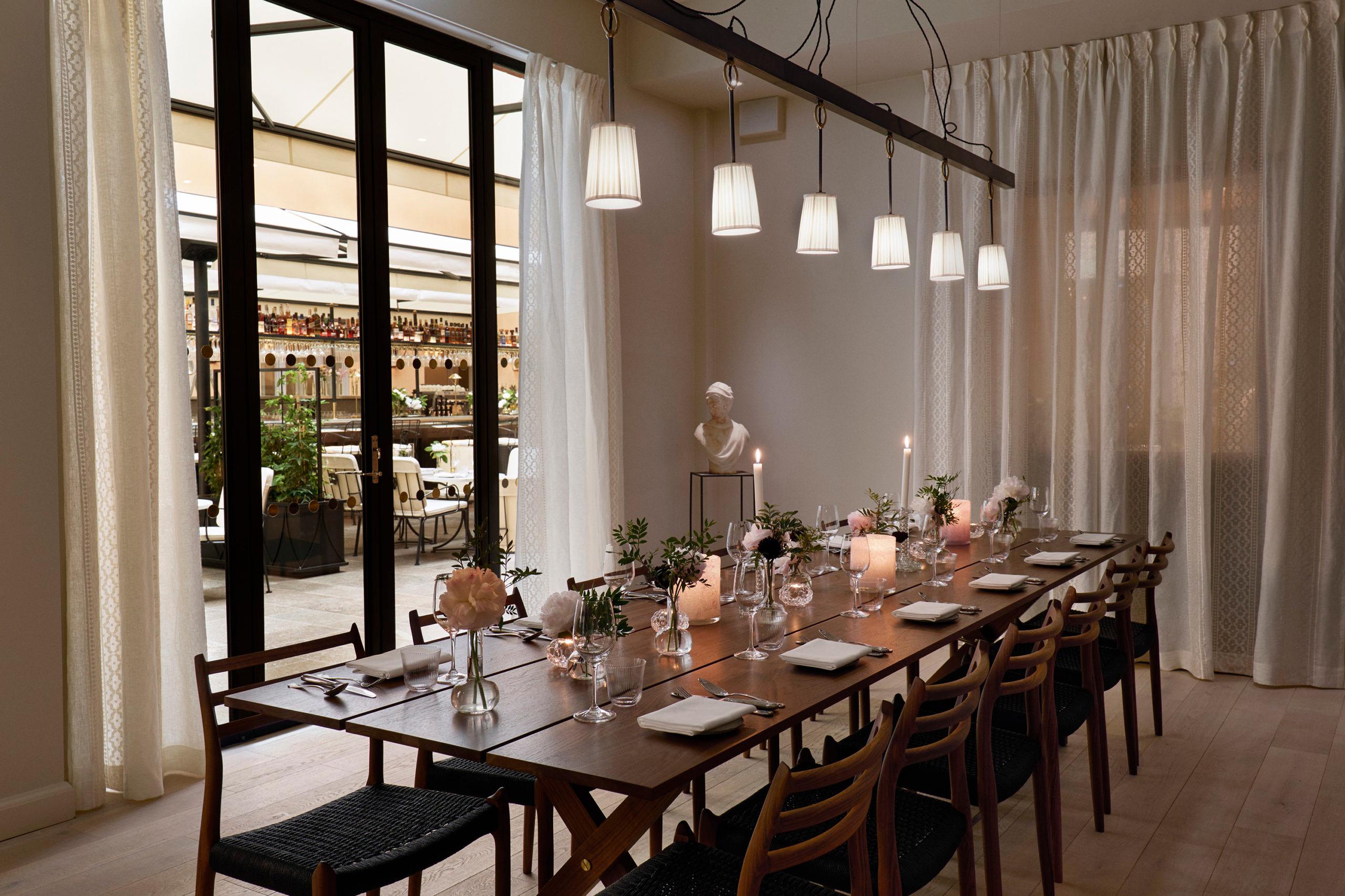 Private dining room with dark wood table, place settings, and floor-to-ceiling windows