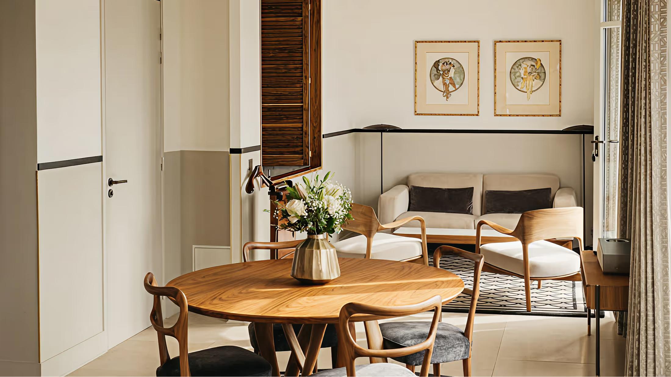 A minimalist dining room with wood table, woven chairs, and framed botanical prints