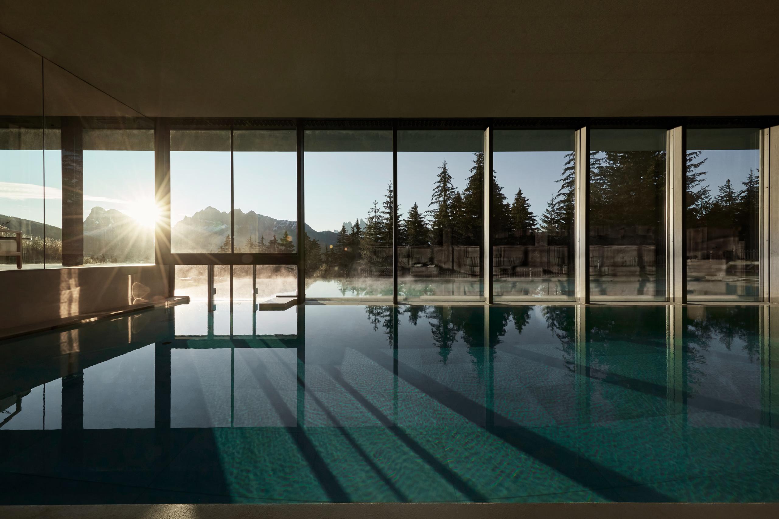 Forestis: a dining or reception area with modern furnishings and mountain views through expansive glass