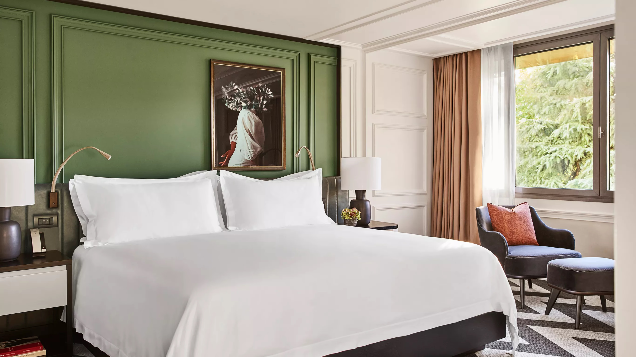 Rosewood Villa Magna: a bedroom with a green accent wall, white linens, and warm wood side tables