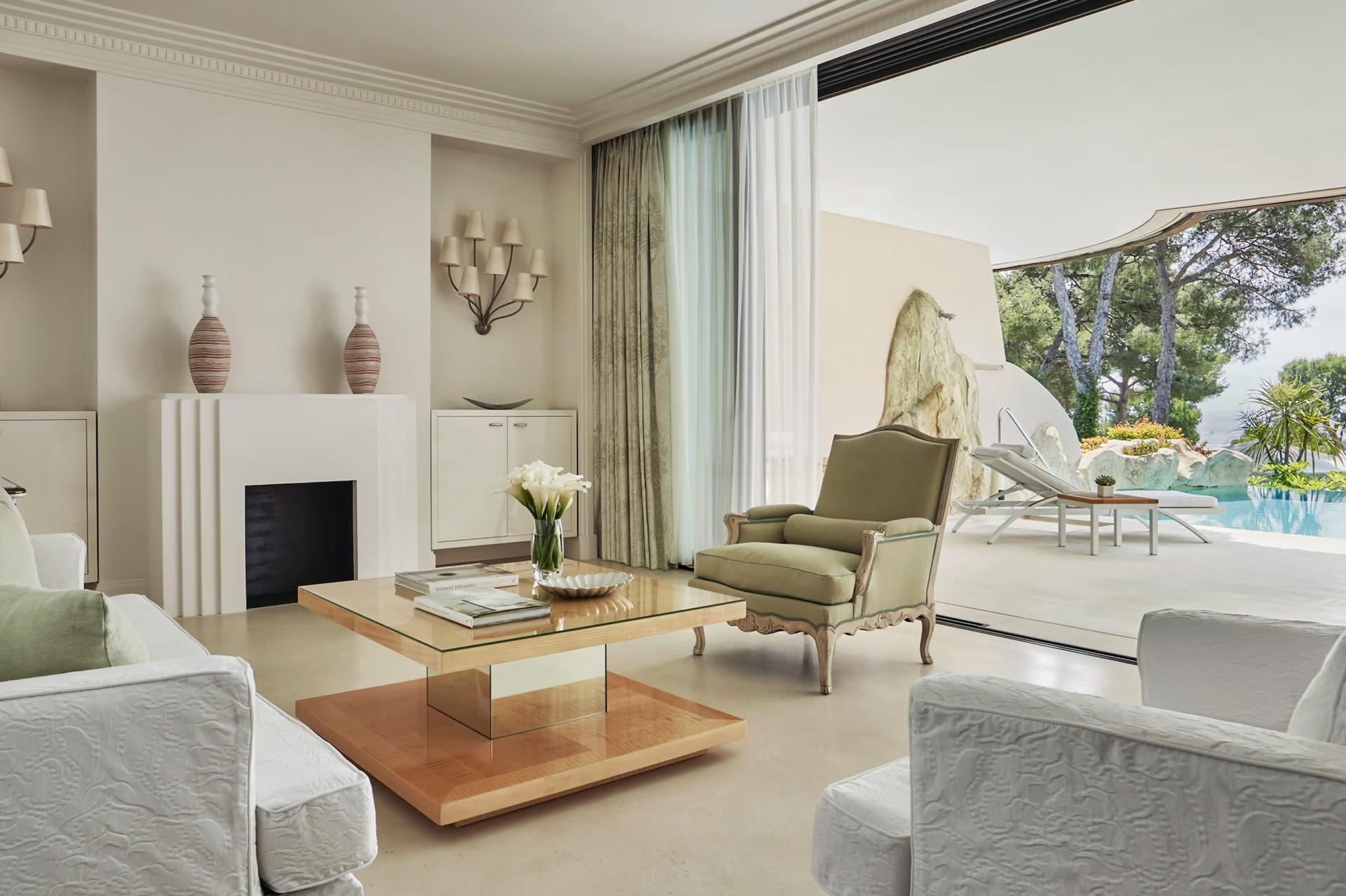 Grand-Hôtel du Cap-Ferrat: suite with fireplace, pale furniture, and terrace overlooking pool and grounds