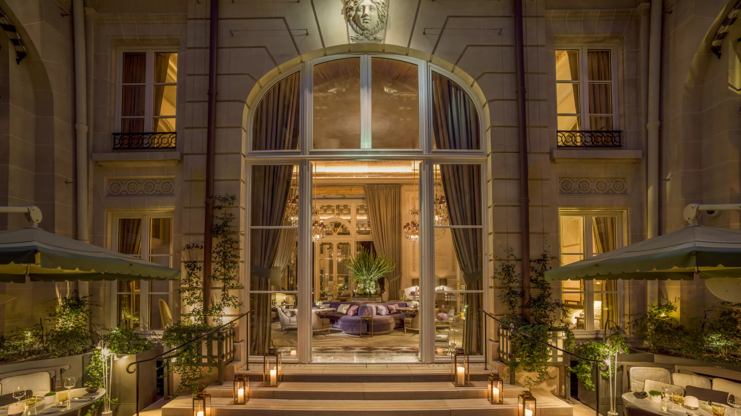 Evening view of arched stone entrance with ornate railings and warm lighting