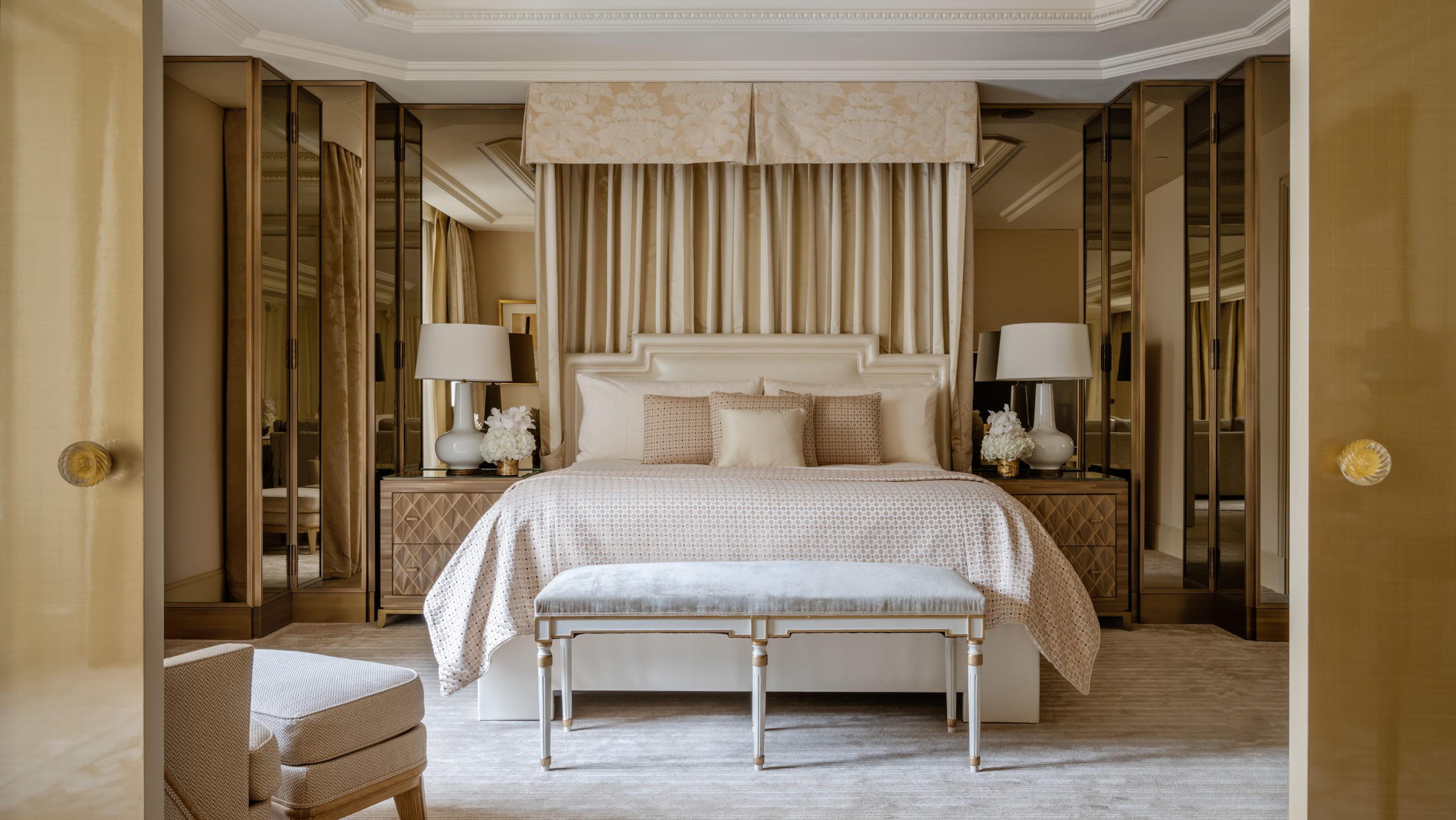 A spacious bedroom with a bed framed by wood wall panels and dress cabinets