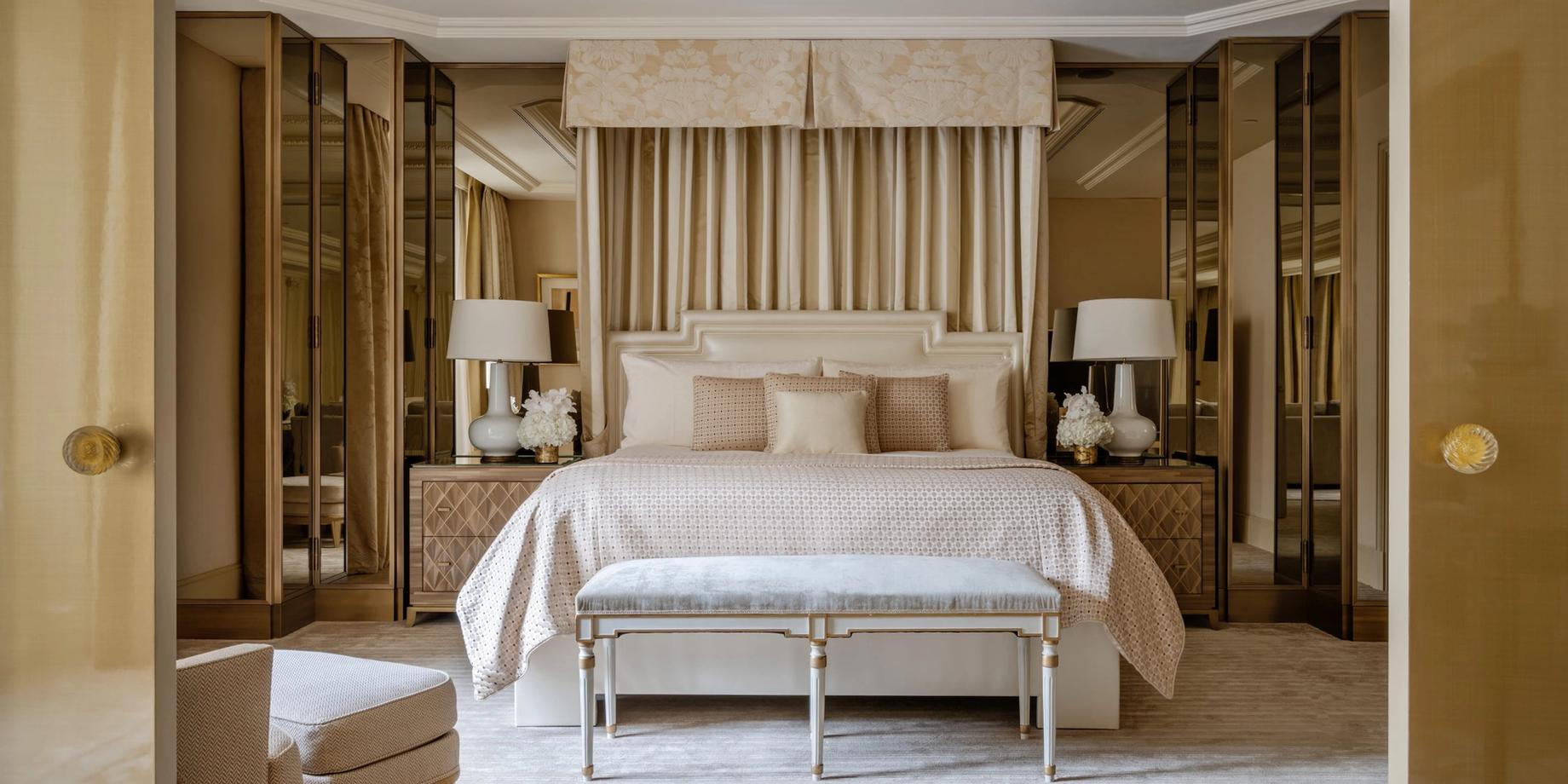 A spacious bedroom with a bed framed by wood wall panels and dress cabinets