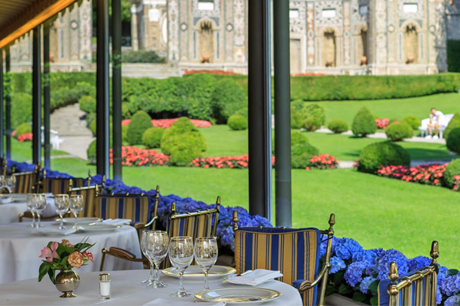 Outdoor dining pavilion with set tables overlooking the lake at dusk