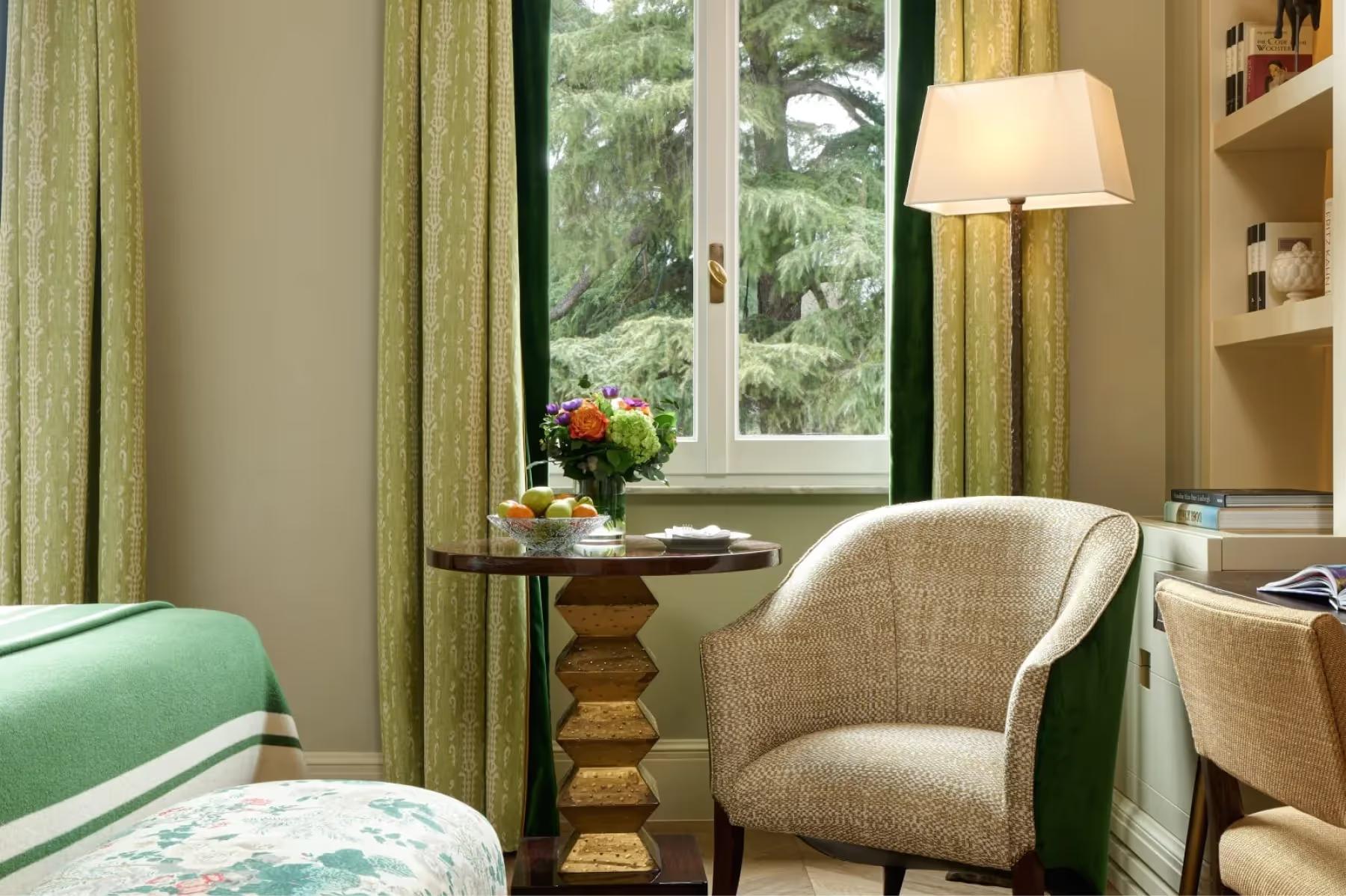 Hotel de Russie: bedroom corner with green curtains, armchair, and bedside lamp near window