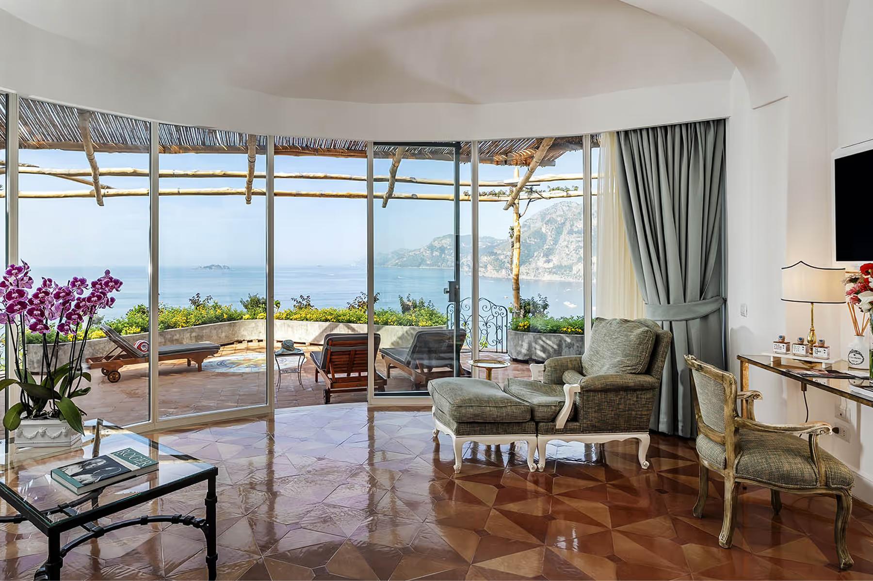Il San Pietro di Positano: suite interior with curved ceiling, window seating, terrace access, light curtains, and sea vistas