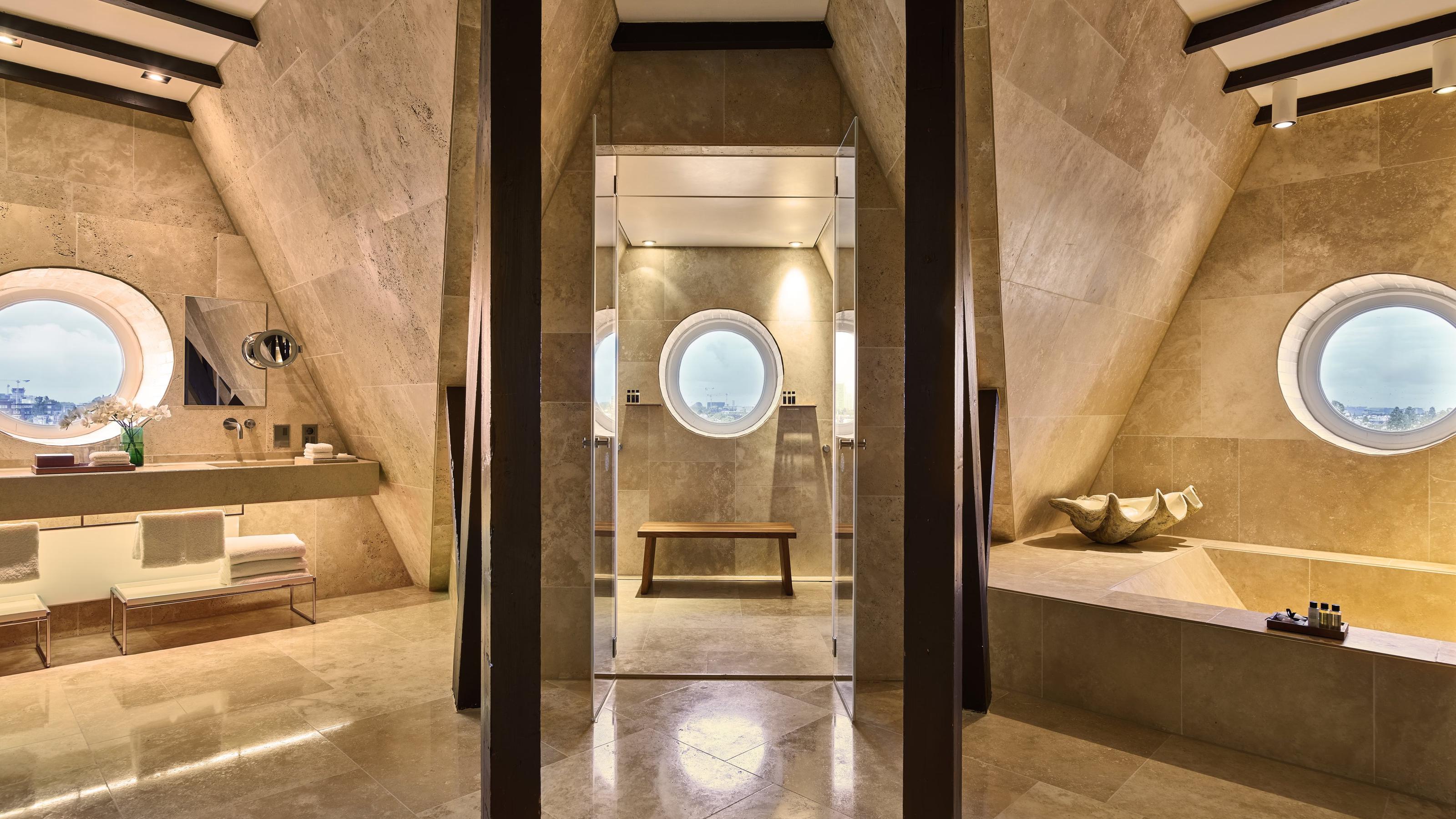 Minimalist spa bathroom with travertine walls, arched mirror niche, and skylights