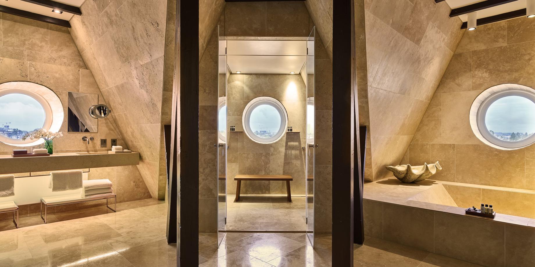 Minimalist spa bathroom with travertine walls, arched mirror niche, and skylights