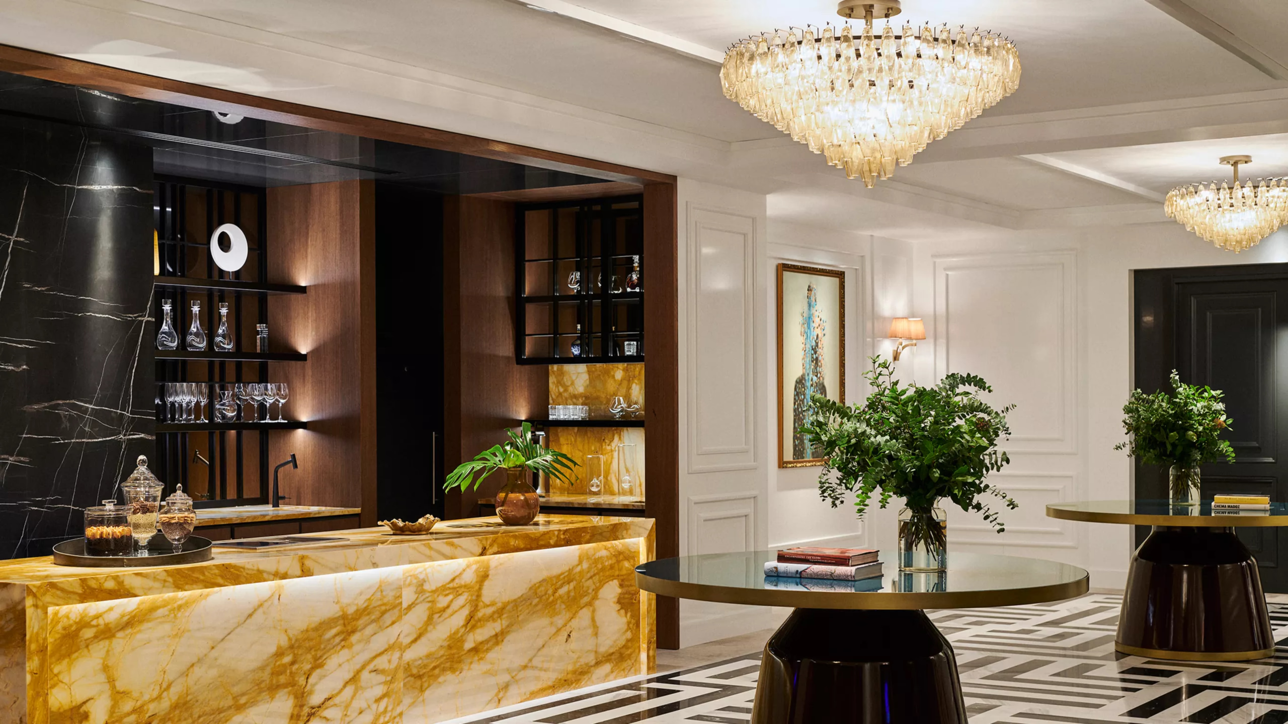 Rosewood Villa Magna: the lobby reception area with gold marble countertop, crystal chandelier, and white finishes
