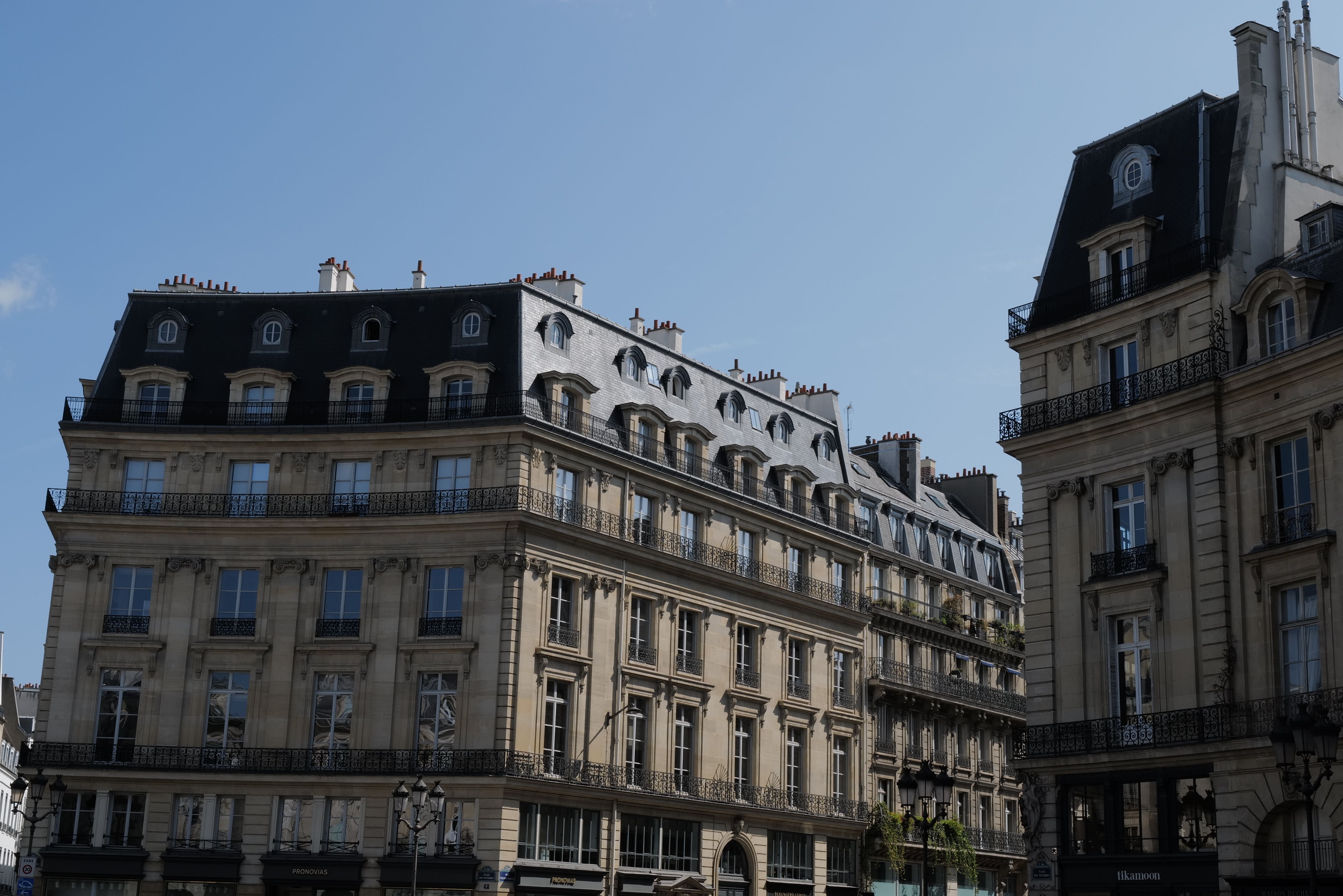 Elegant Haussmann buildings with wrought-iron balconies beneath a clear blue Paris sky.