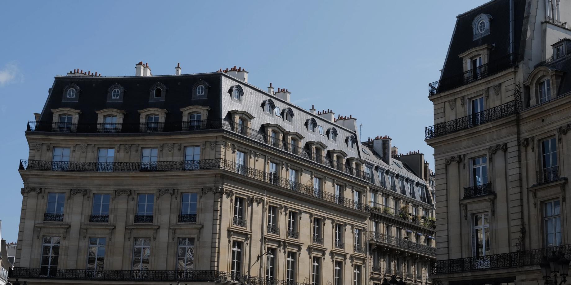 Elegant Haussmann buildings with wrought-iron balconies beneath a clear blue Paris sky.
