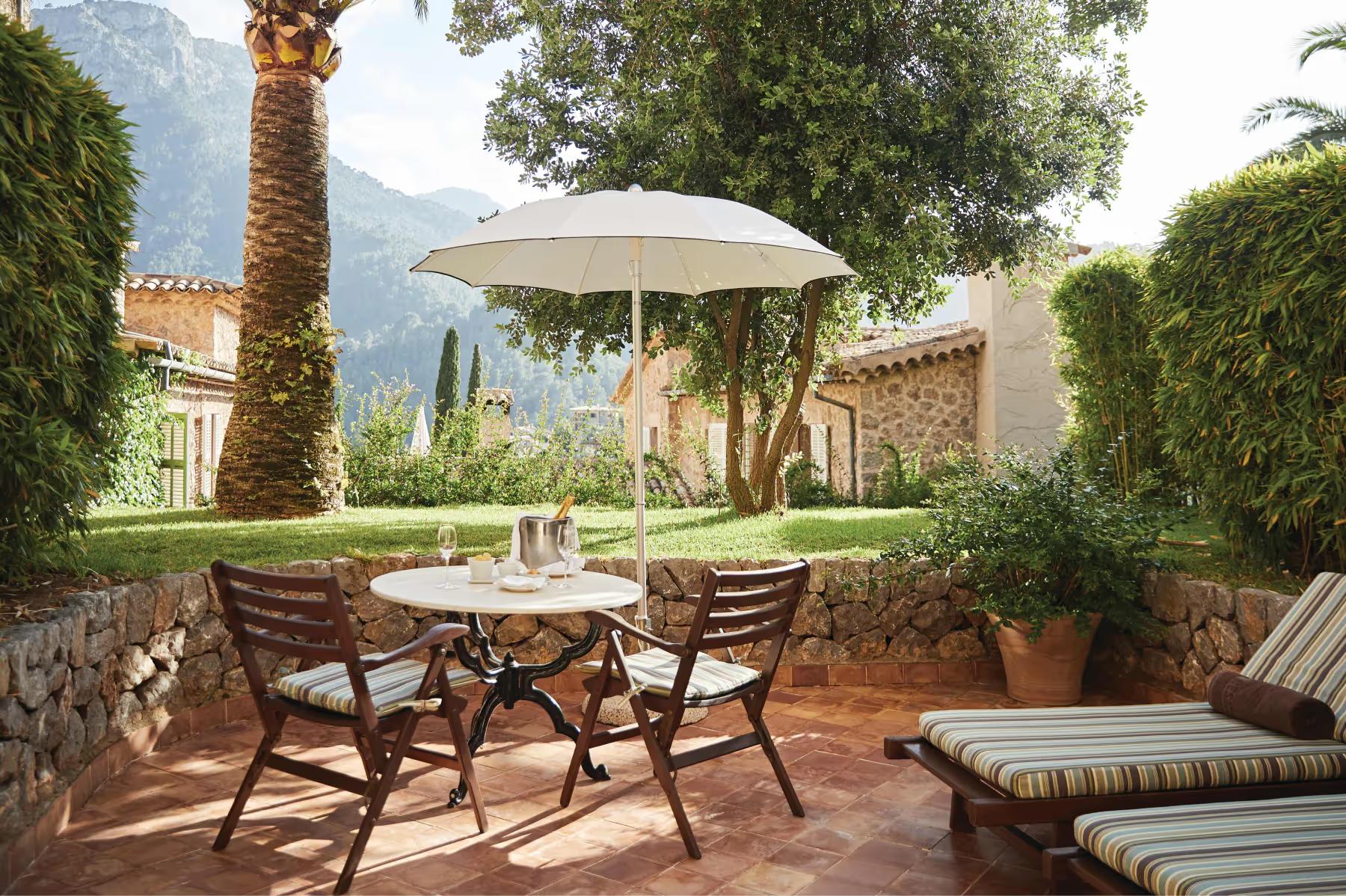 La Residencia: shaded courtyard with dining table, chairs, and turquoise pool surrounded by cypress trees