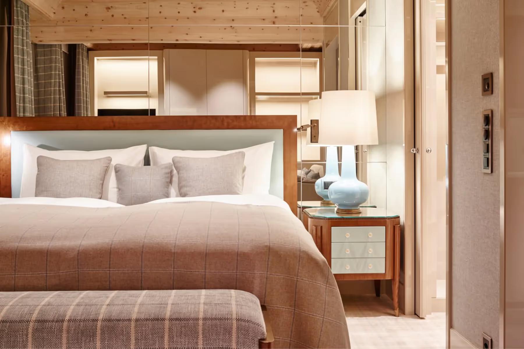 A bedroom with wood-paneled ceiling and king bed in warm neutral tones