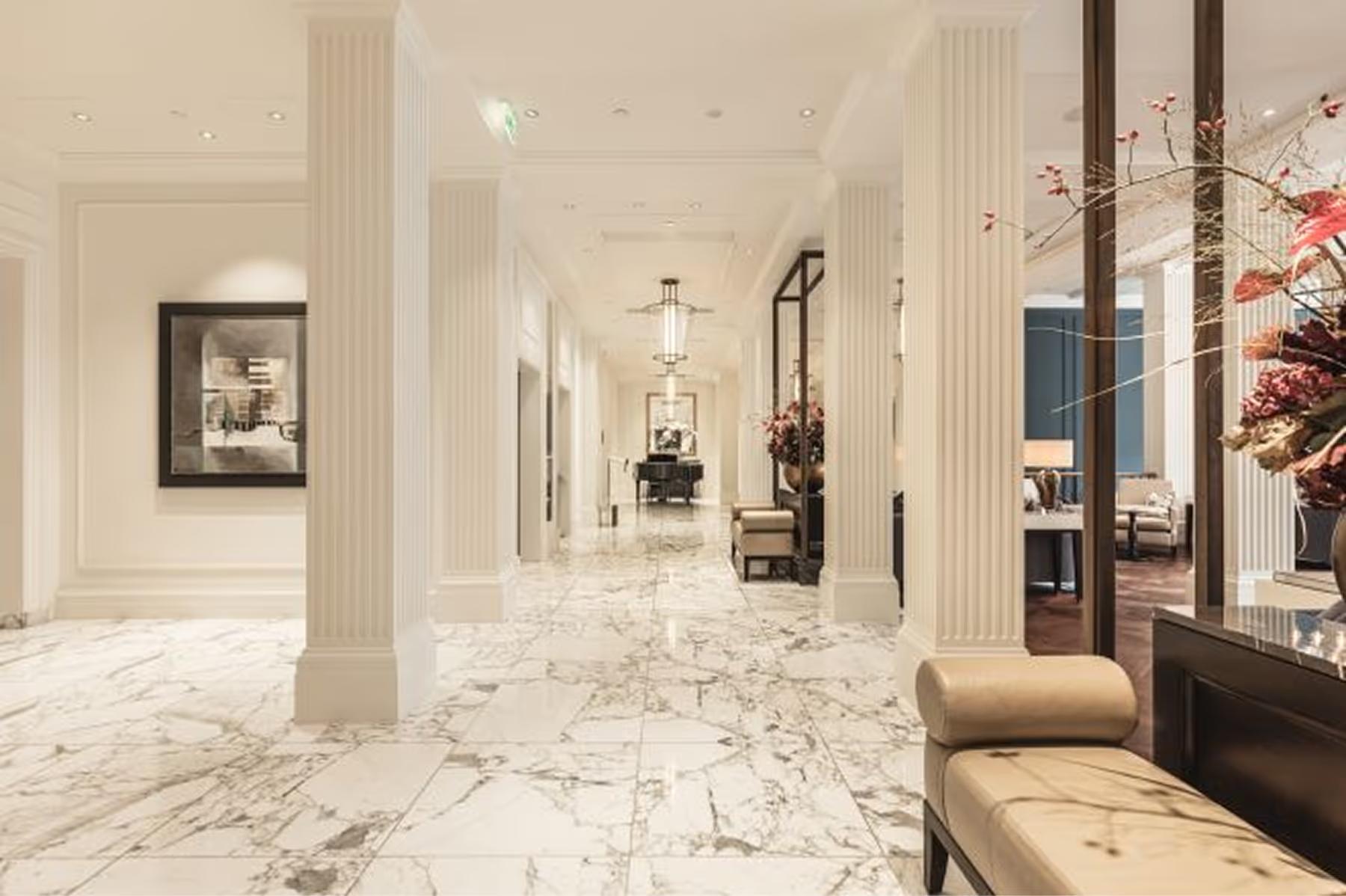 Waldorf Astoria Amsterdam: a gallery hallway with marble floors, tall columns, artwork, and cream architectural details